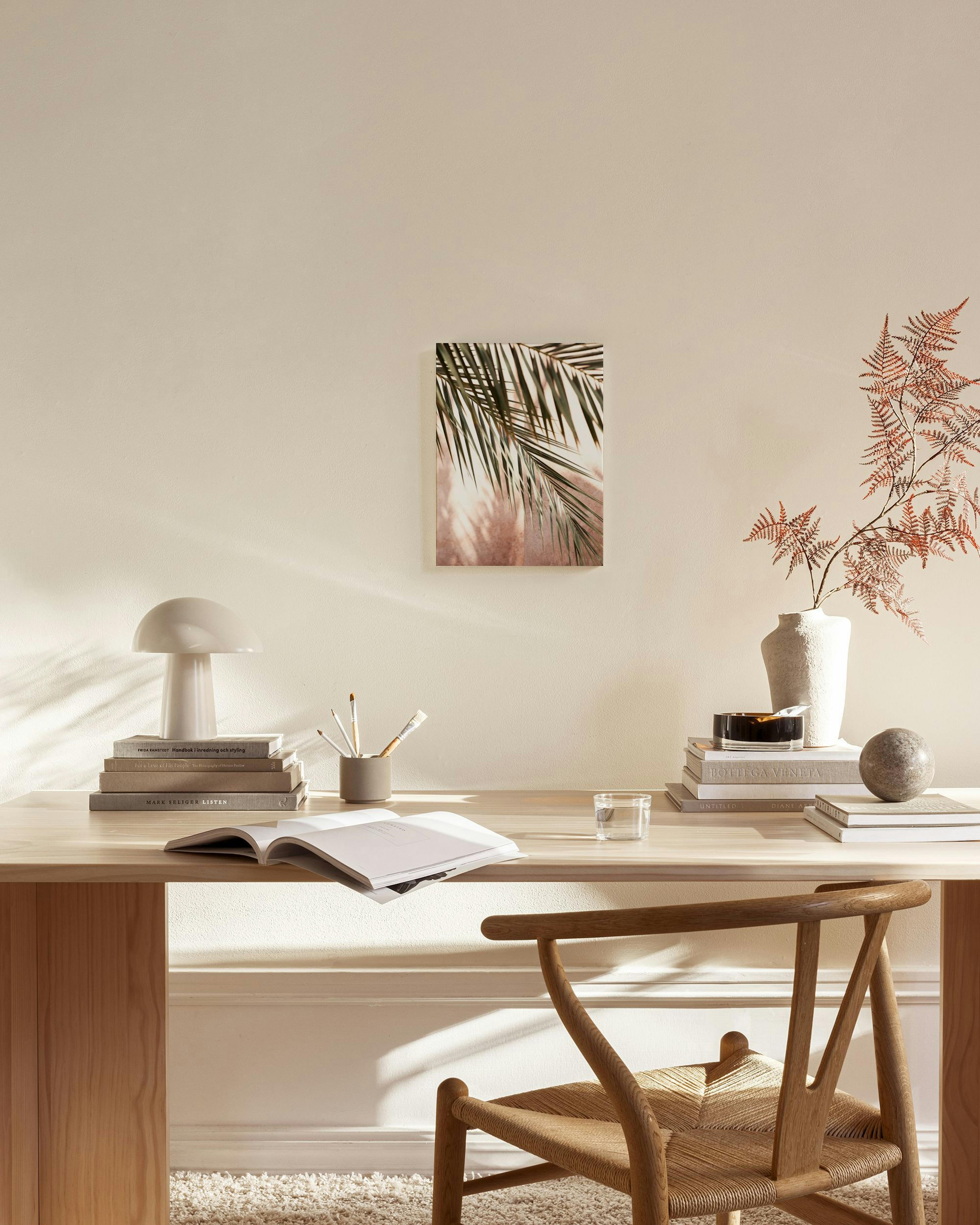 Kanvaasi palmunlehdistä, joissa varjot heijastuvat roosanväriselle taustalle, modernissa olohuoneessa.