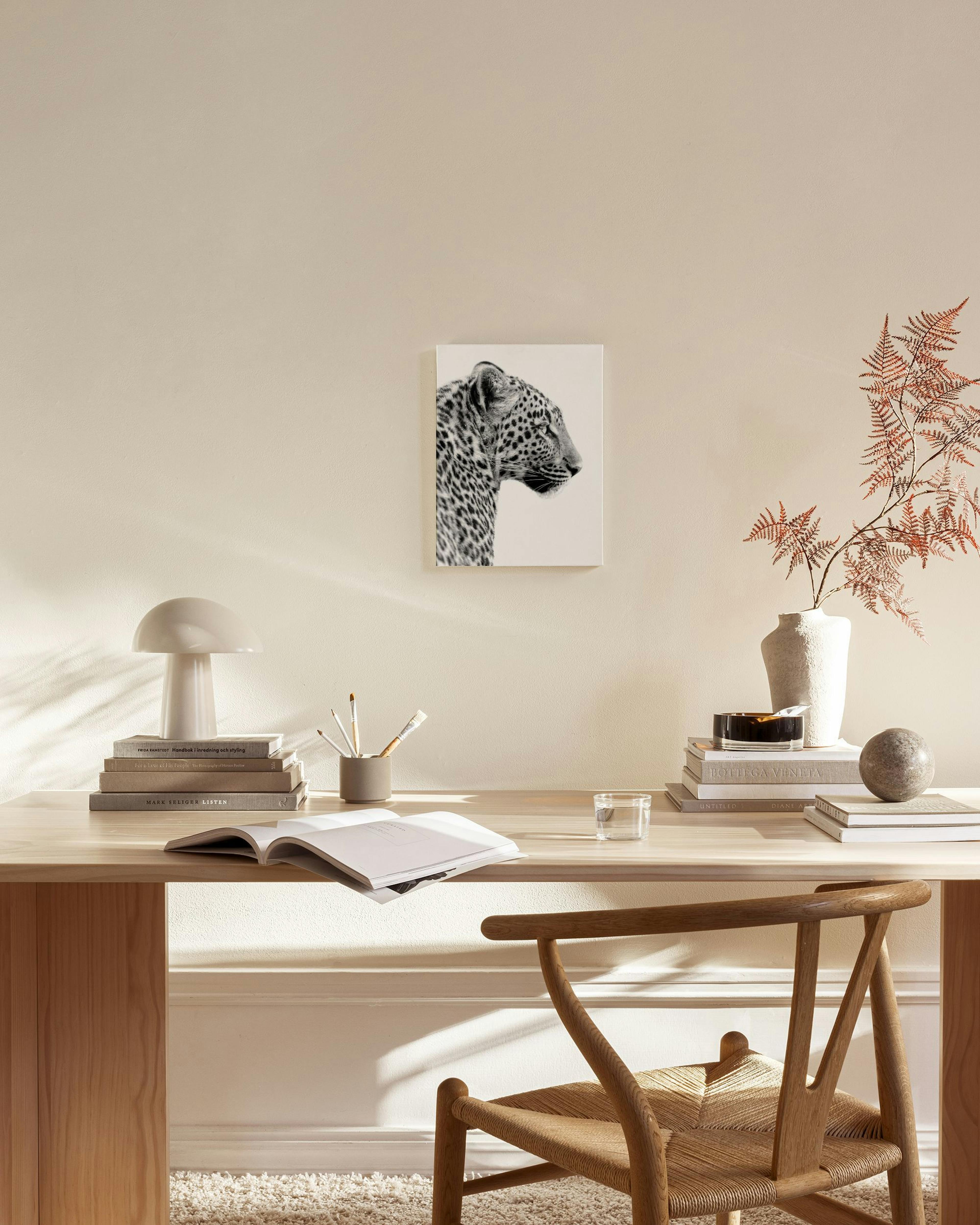 Zwart-wit canvas van een luipaardkop in profiel, hangend boven een houten dressoir in een modern interieur.