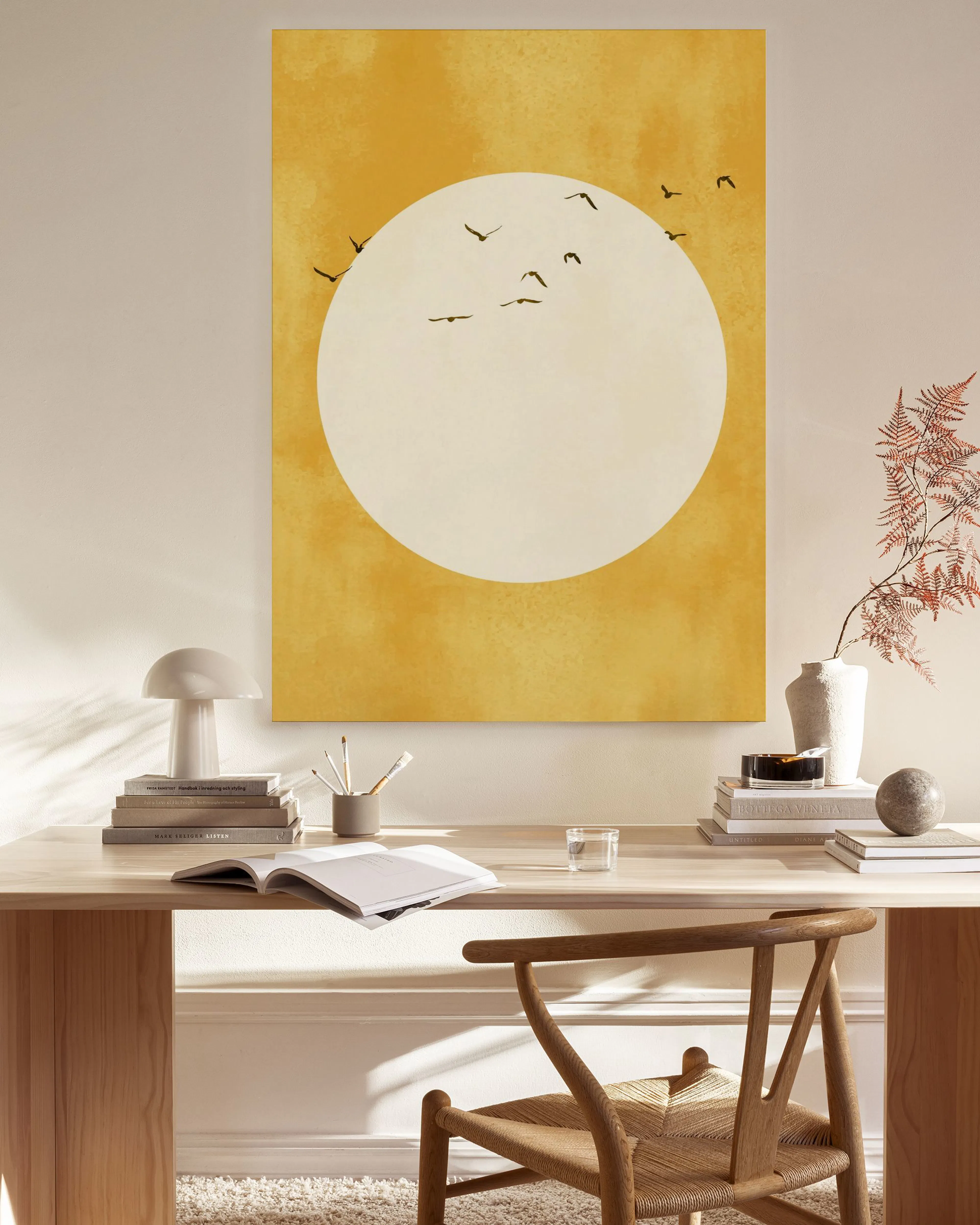 Leinwandbild mit gelbem Himmel, weißem Kreis und schwarzen Vogelsilhouetten, über einer Kommode in einem Wohnzimmer.