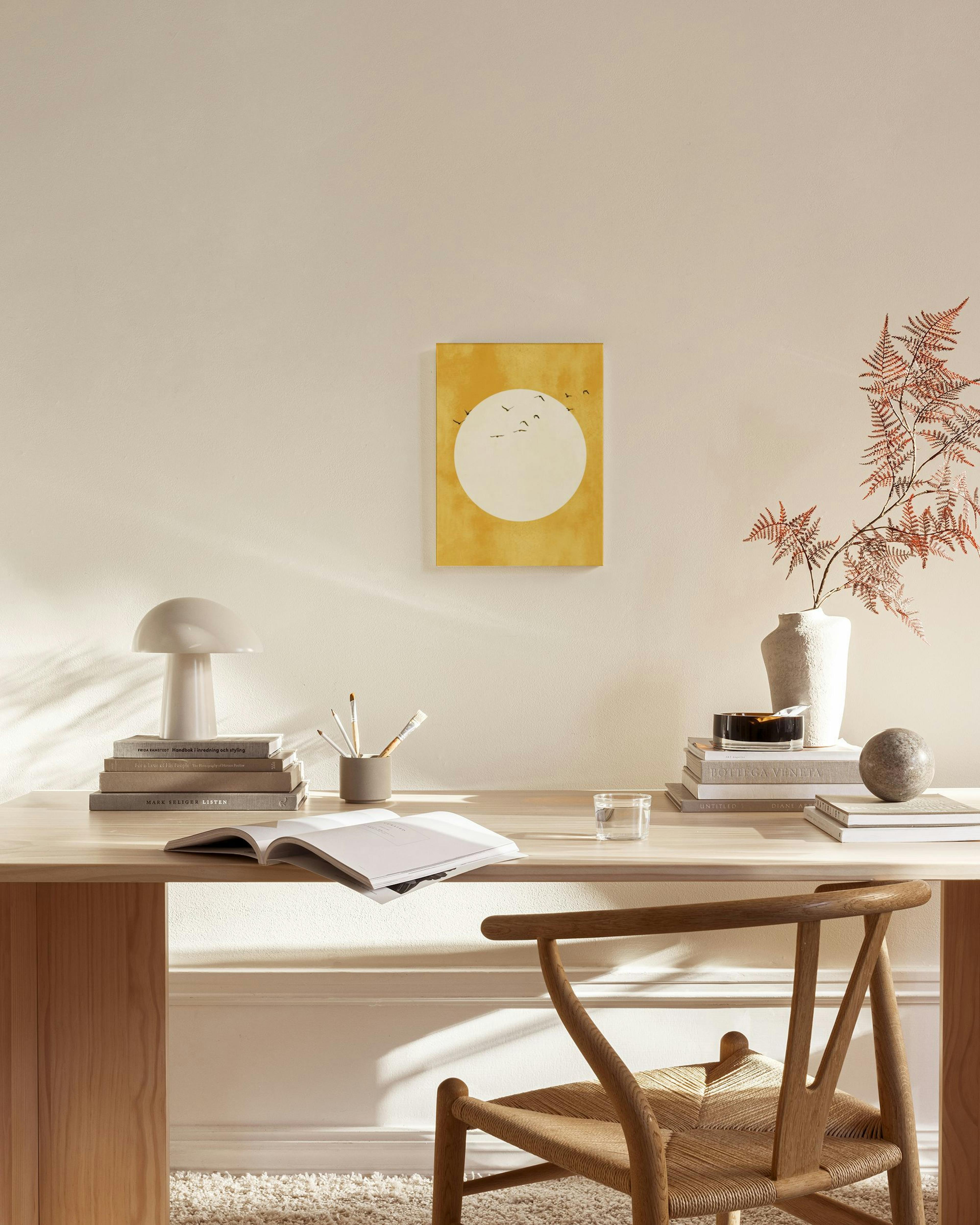 Keltainen kanvaasi, jossa valkoinen ympyrä ja lintuparvi, ripustettuna modernissa olohuoneessa.