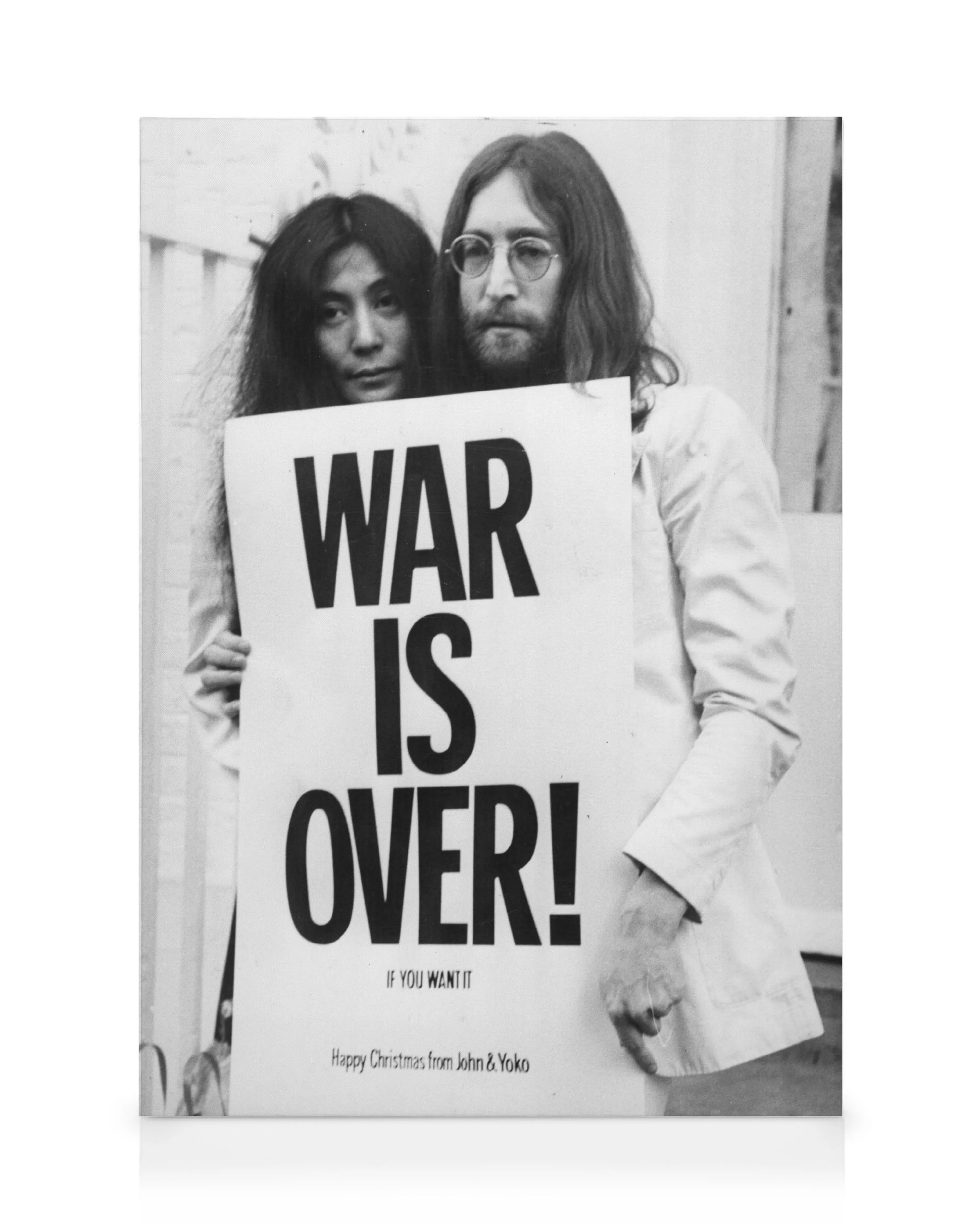 Mustavalkoinen kanvaasi, jossa John Lennon ja Yoko Ono pitävät WAR IS OVER! -kylttiä.