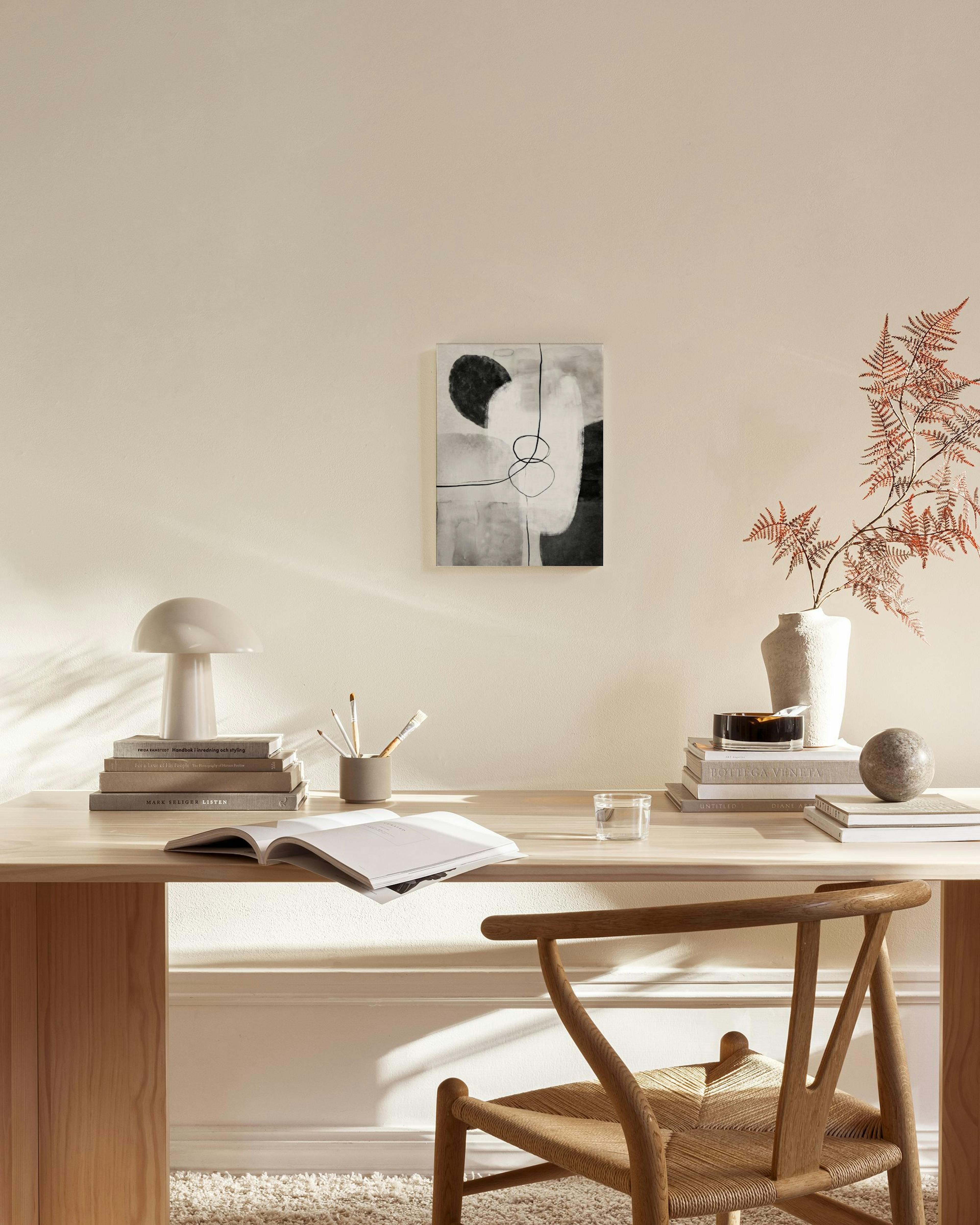 Obraz na płótnie z czarno-białymi abstrakcyjnymi kształtami i liniami, zawieszony w nowoczesnym salonie nad drewnianą komodą.