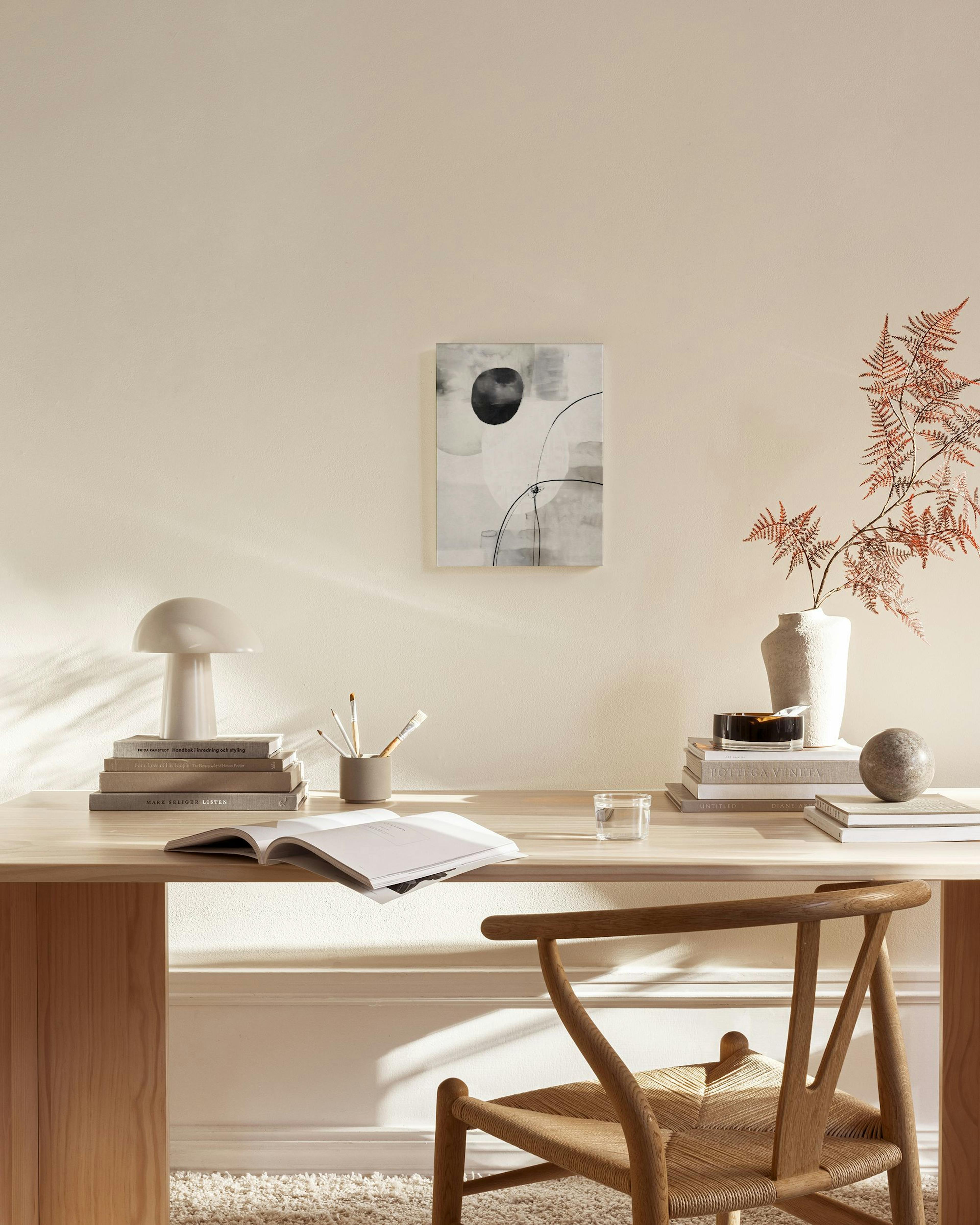 Mustavalkoinen abstrakti kanvaasi orgaanisilla muodoilla ja ohuilla viivoilla, ripustettuna moderniin olohuoneeseen.