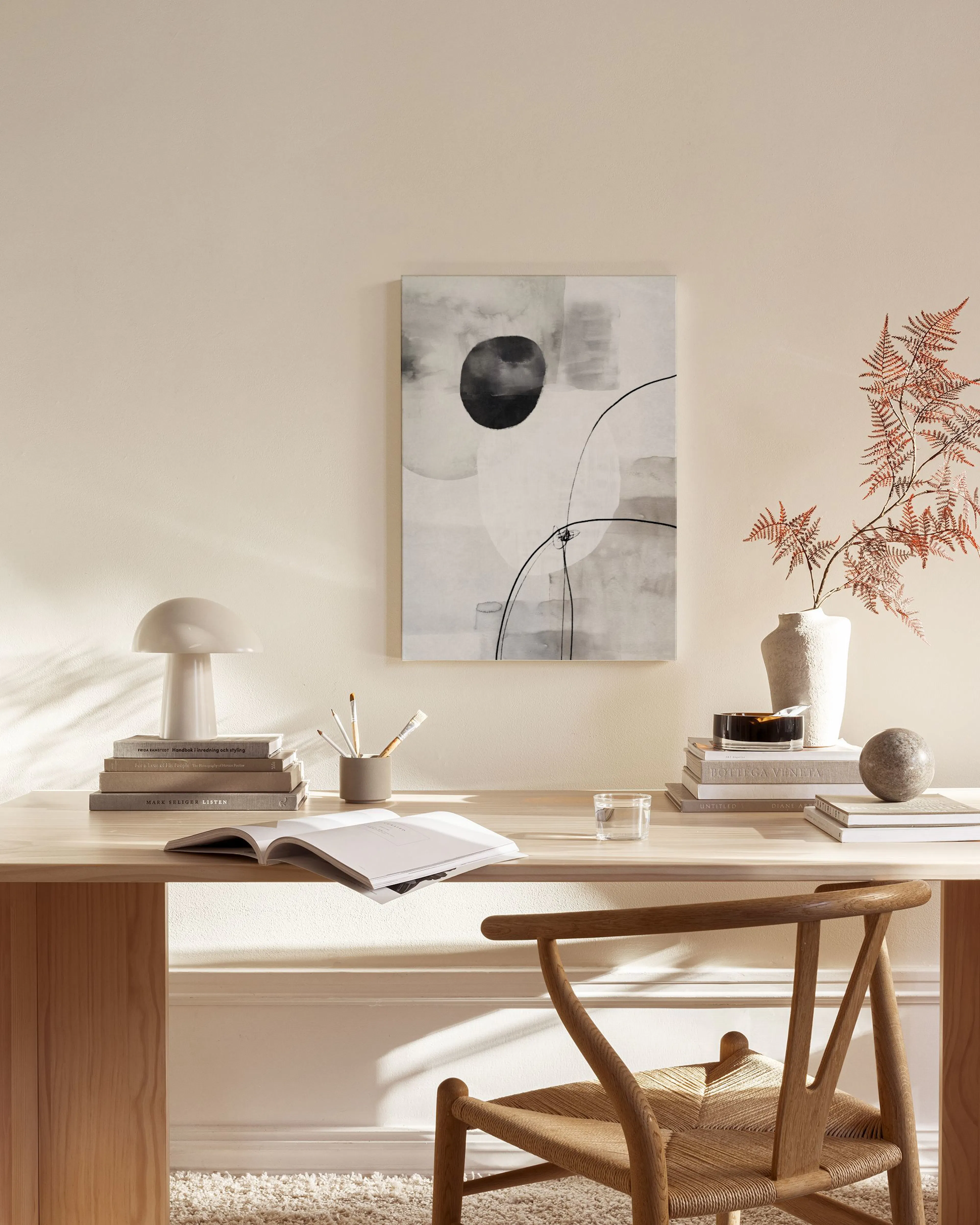 Abstract canvas print with black, gray, and white circular shapes and flowing lines, hanging in a minimalist living room.