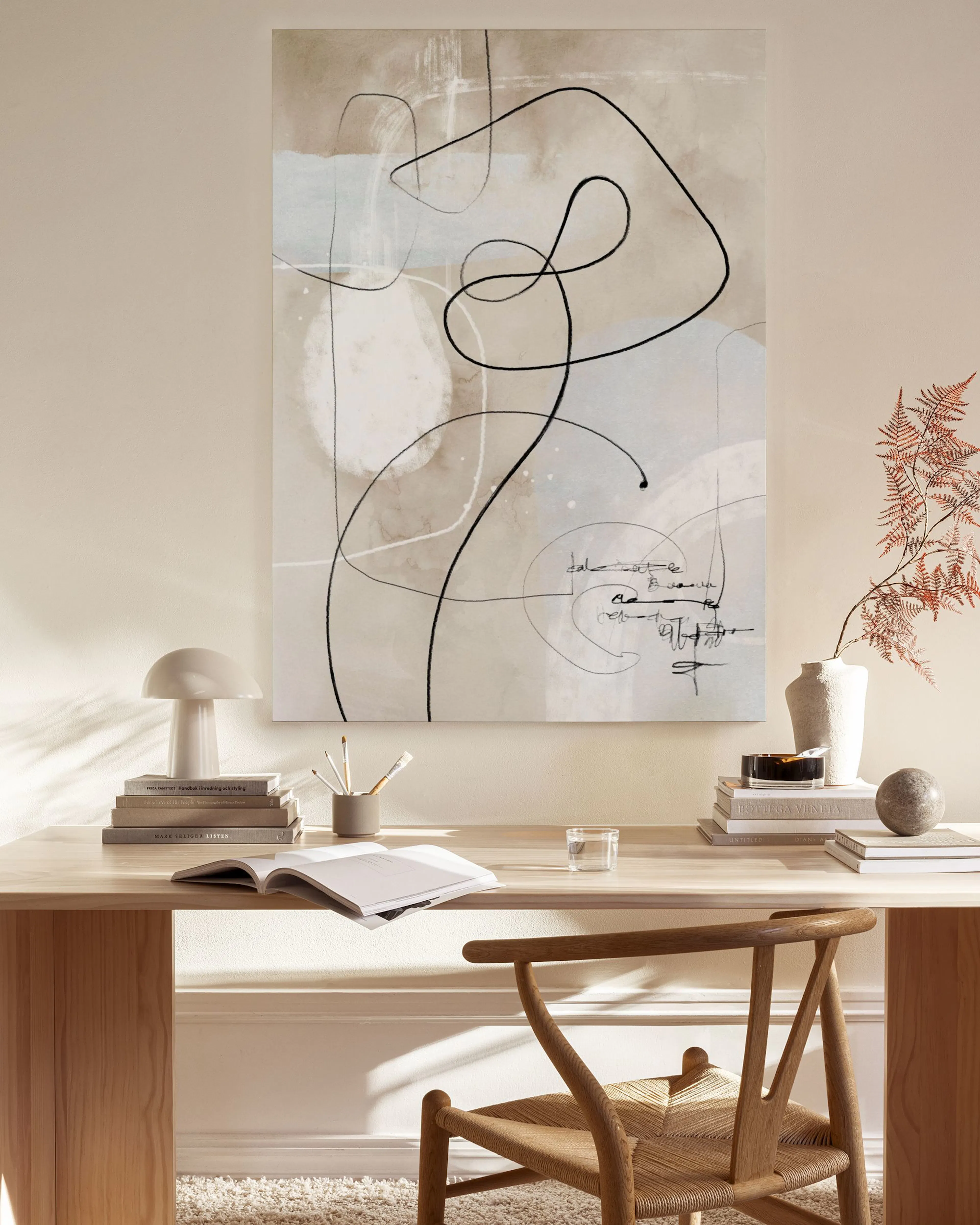 An abstract canvas print with black flowing lines and subtle beige, grey, and white shapes, hanging in a minimalist living room.