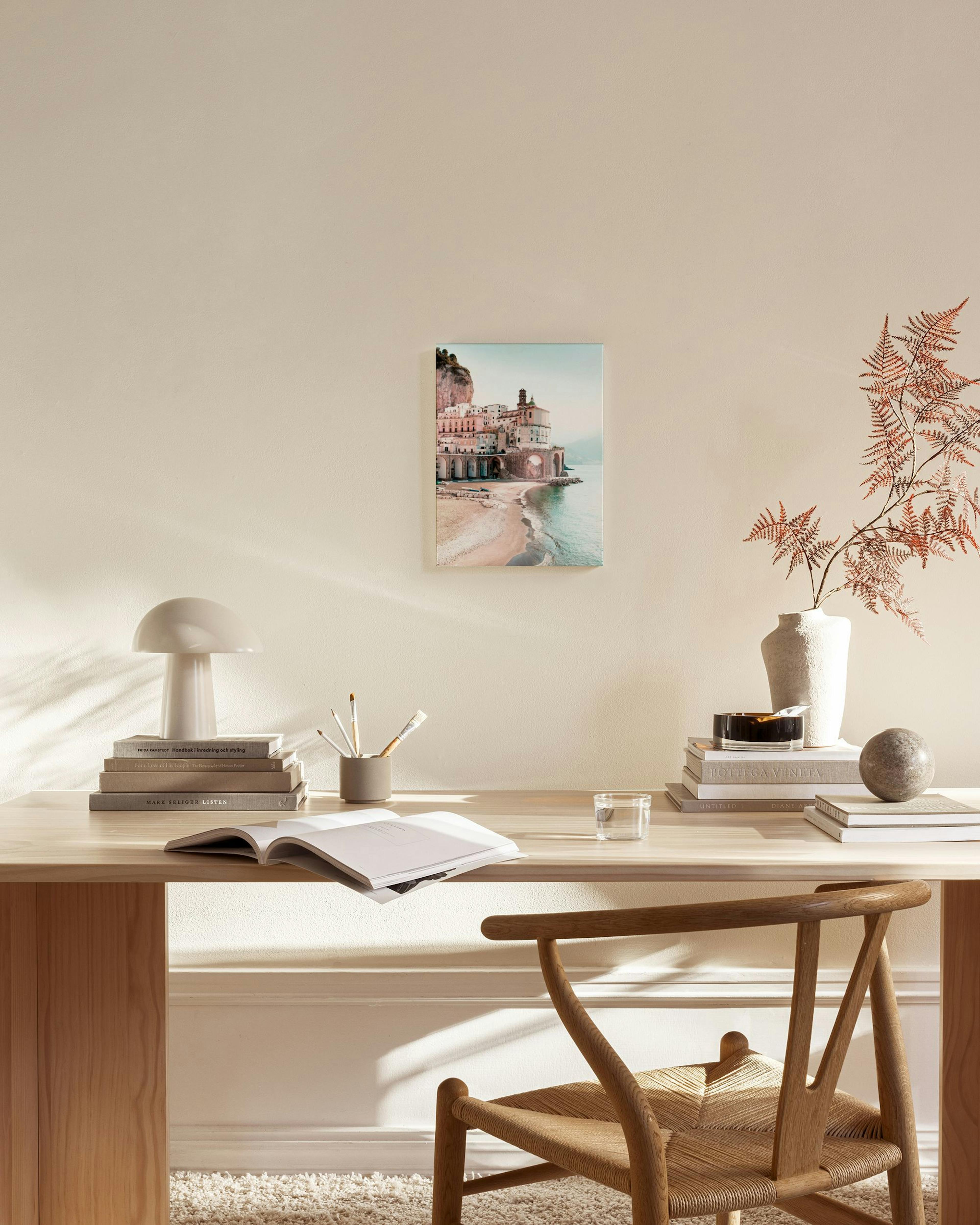 A canvas print of a scenic Italian coastal town with buildings on cliffs and a beach, displayed in a neutral-toned living room.