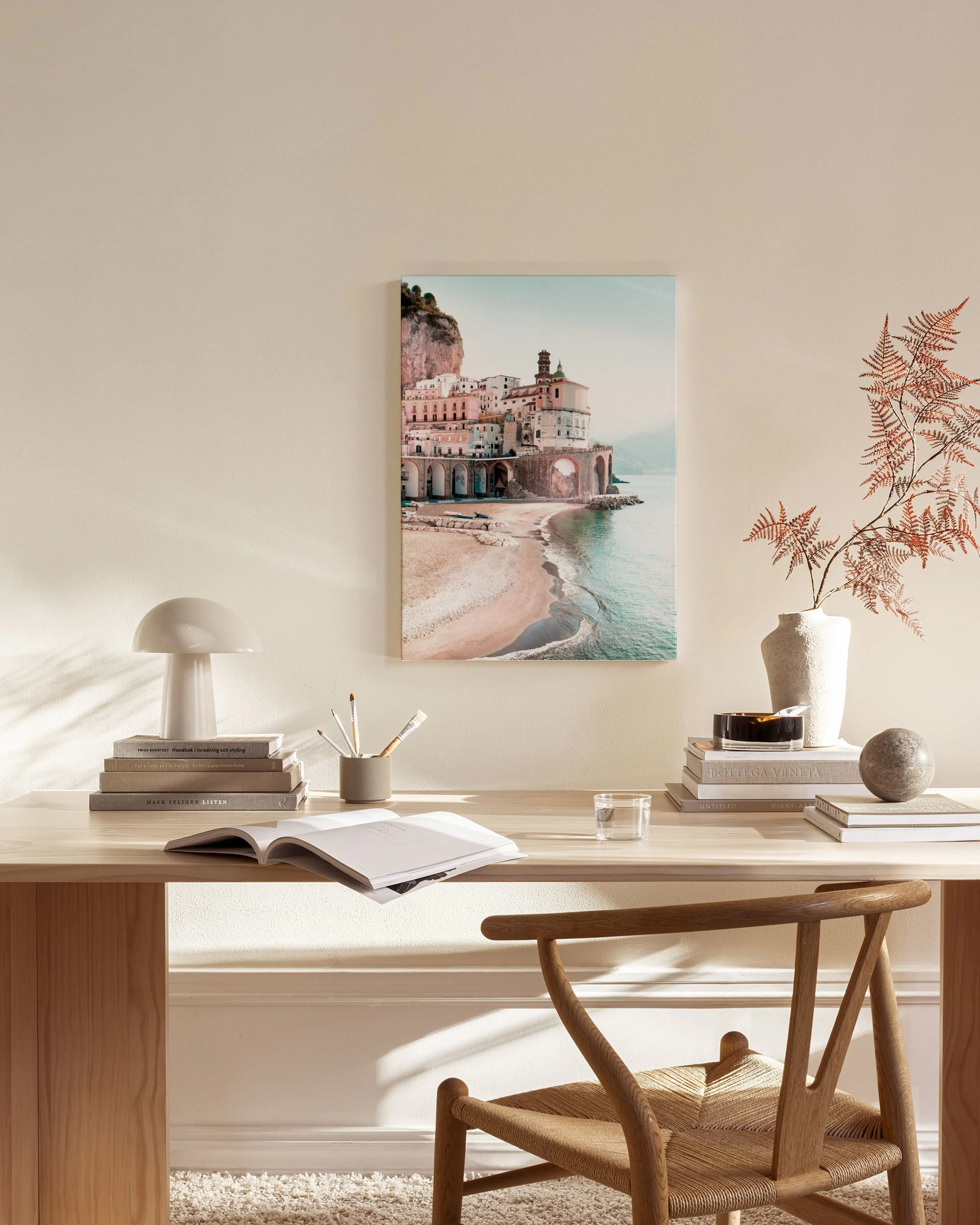 A canvas print of a scenic Italian coastal town with buildings on cliffs and a beach, displayed in a neutral-toned living room.