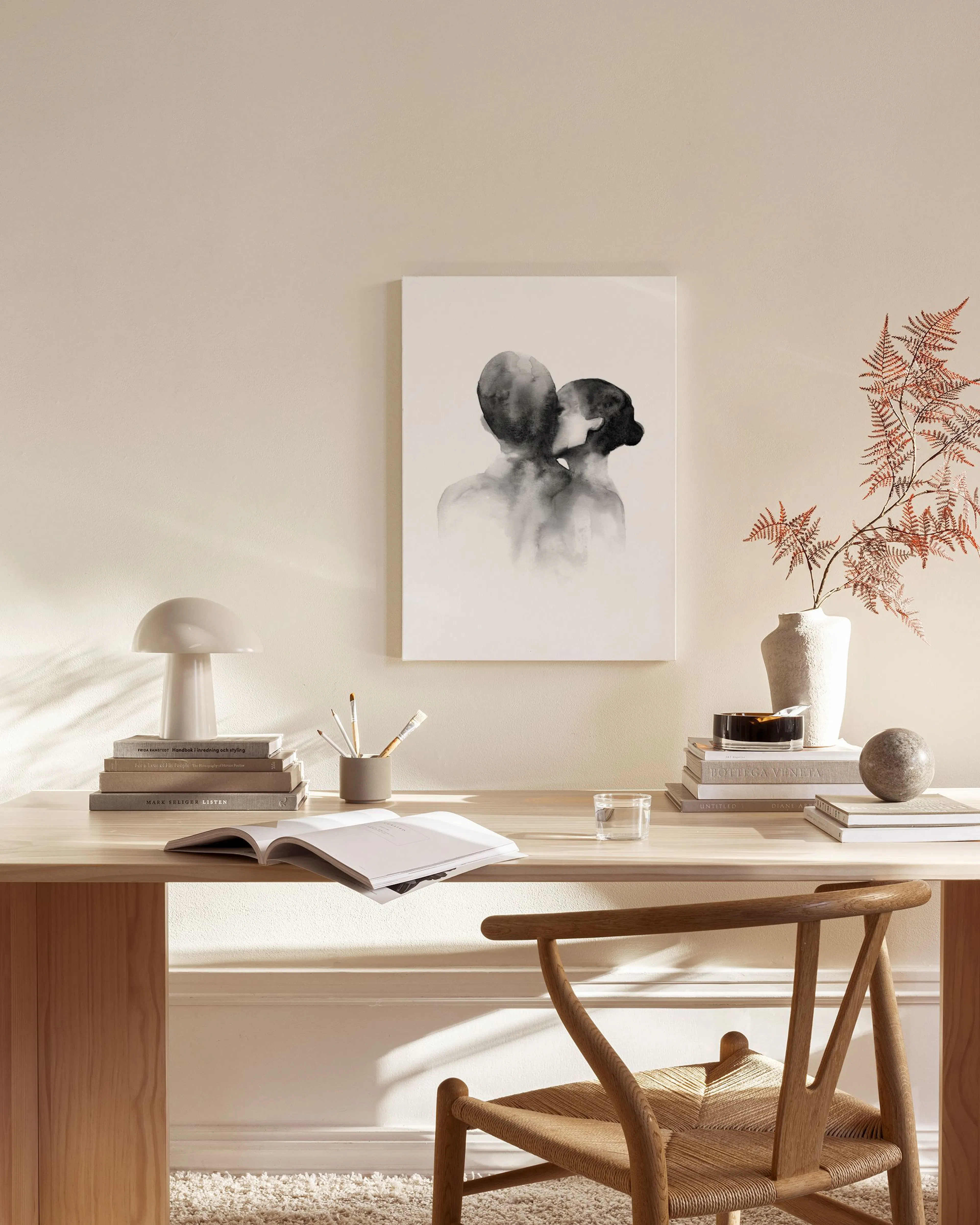 Leinwandbild mit zwei abstrakten Silhouetten, die sich küssen, in einem hellen Wohnzimmer über einem Sideboard.