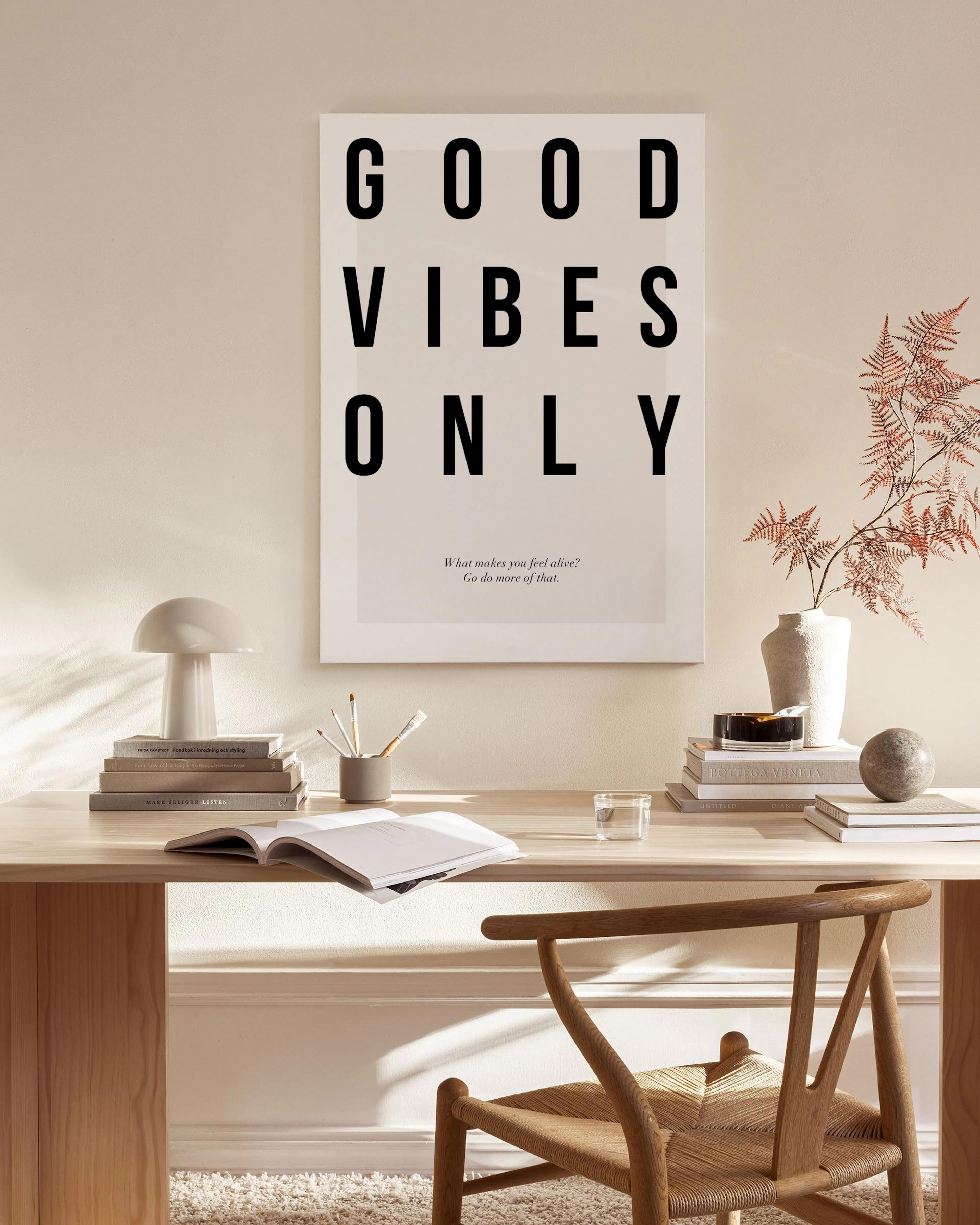 Lienzo con la frase GOOD VIBES ONLY en letras negras, colgado sobre un mueble de madera en una sala moderna.