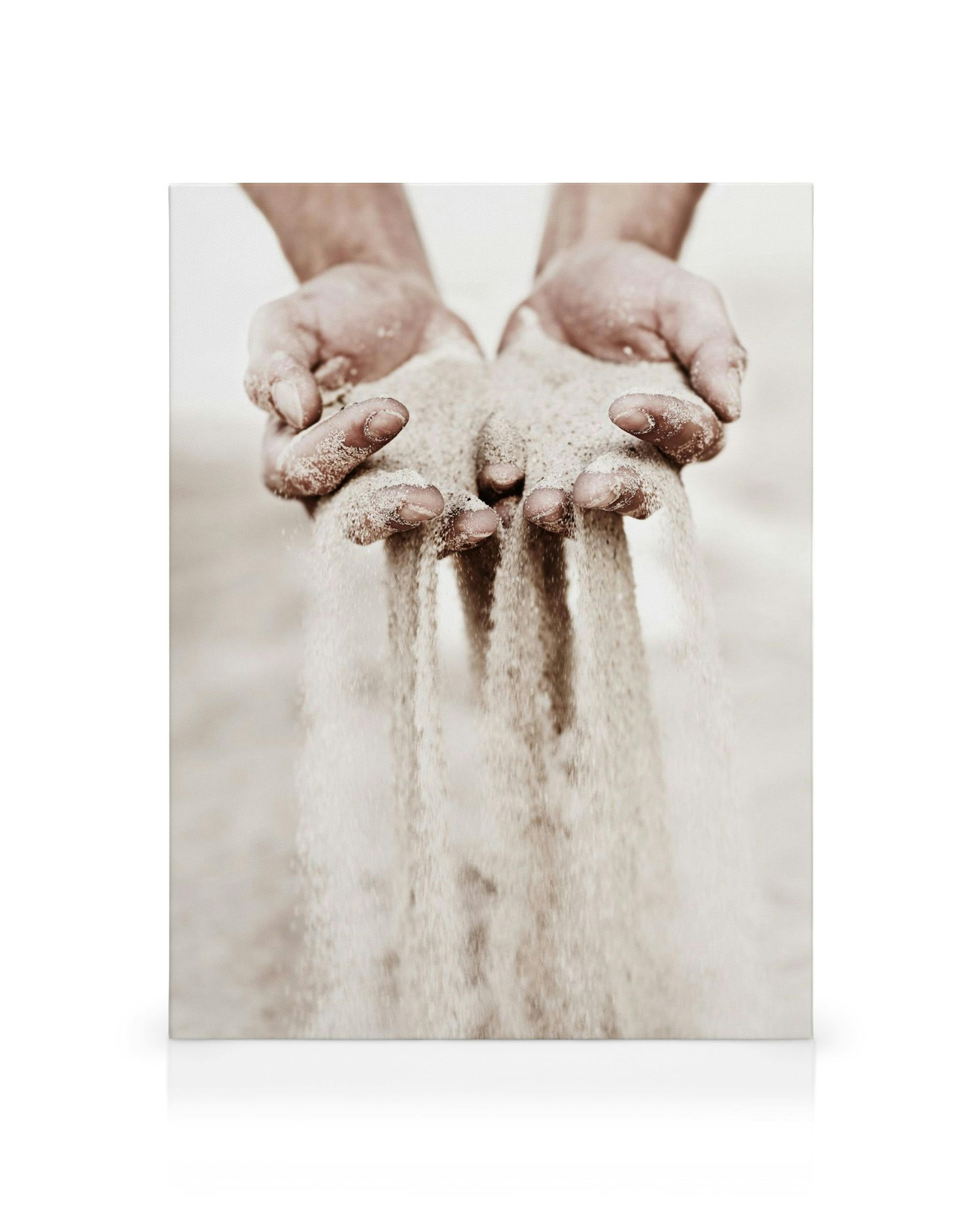 Hände, die Sand rieseln lassen, in warmen Sepia-Tönen, symbolisieren Vergänglichkeit und Achtsamkeit.