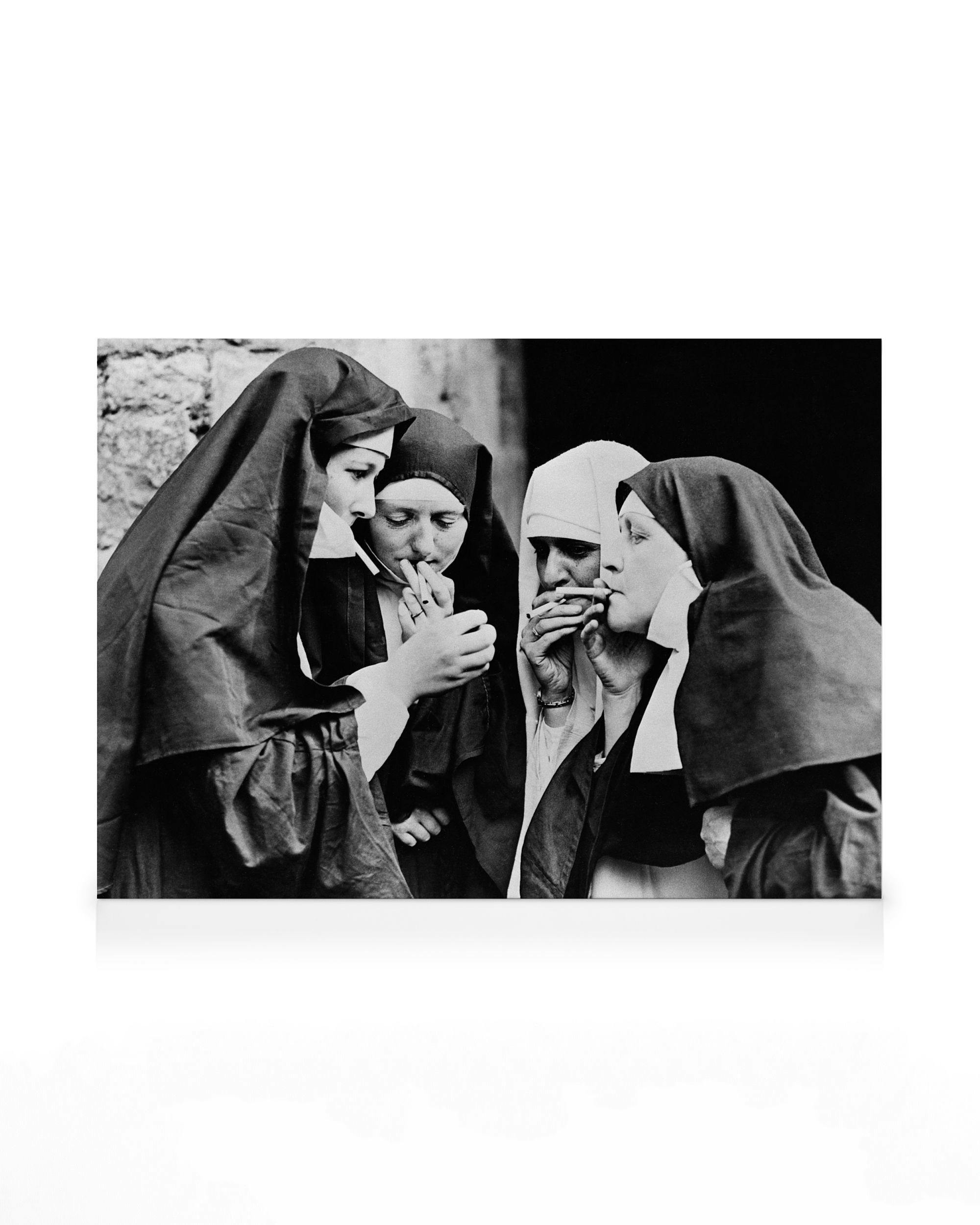 Toile noir et blanc de quatre religieuses fumant des cigarettes, une allumant la cigarette dune autre.
