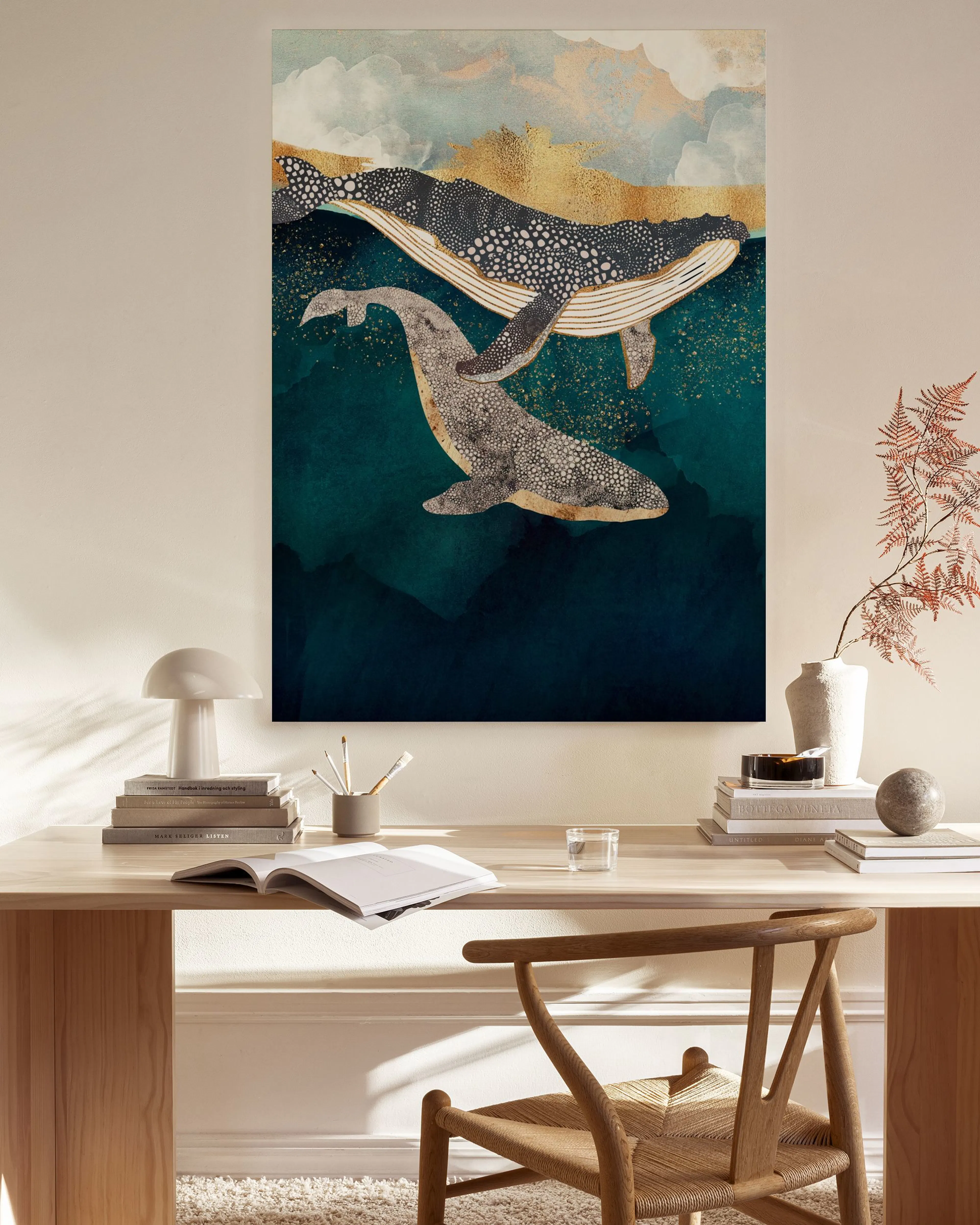 A canvas print of two gray and white whales in deep blue water with golden abstract mountains, displayed in a modern living room