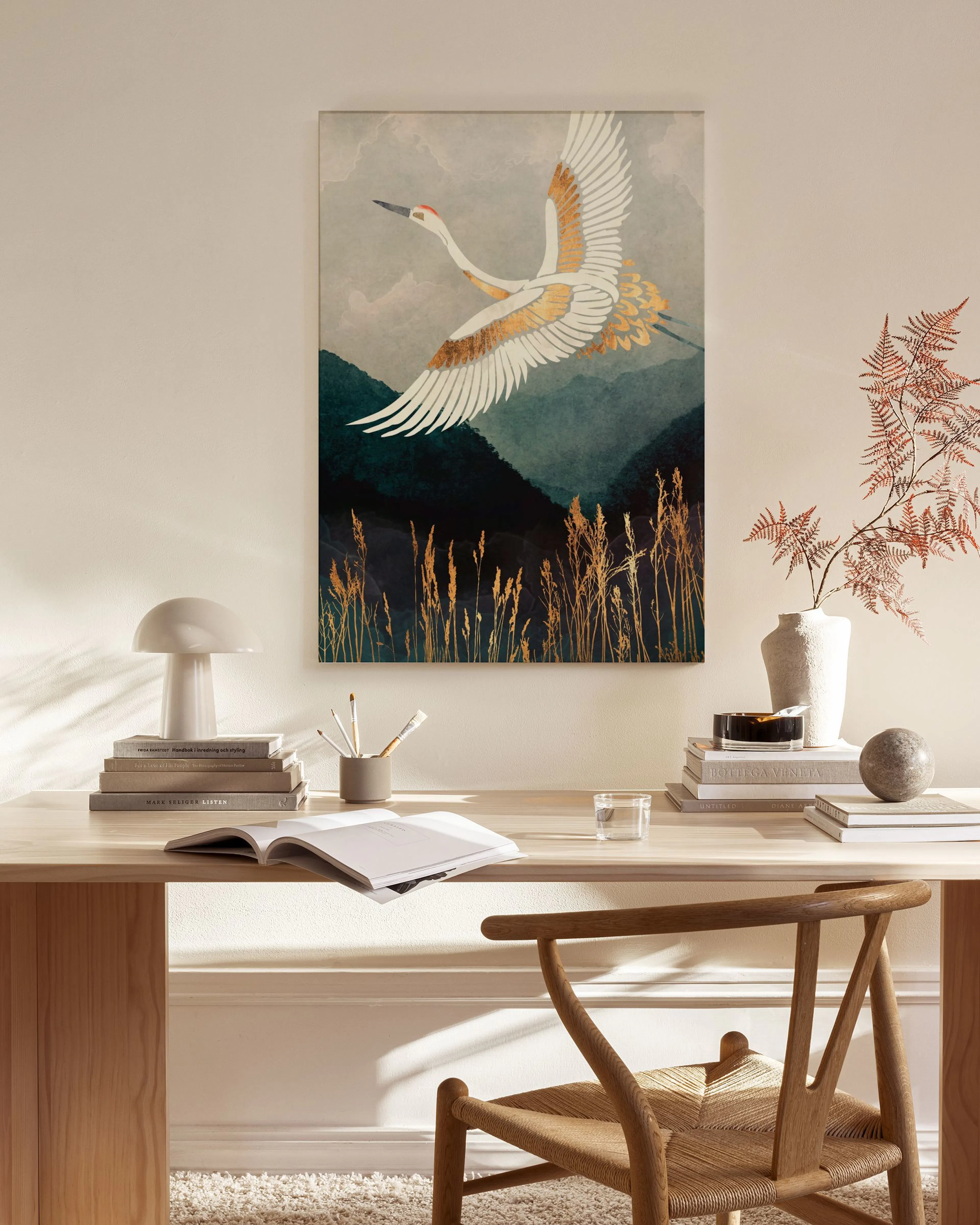 Leinwandbild mit fliegendem Kranich über Bergen und Schilf, aufgehängt in einem hellen Wohnzimmer.
