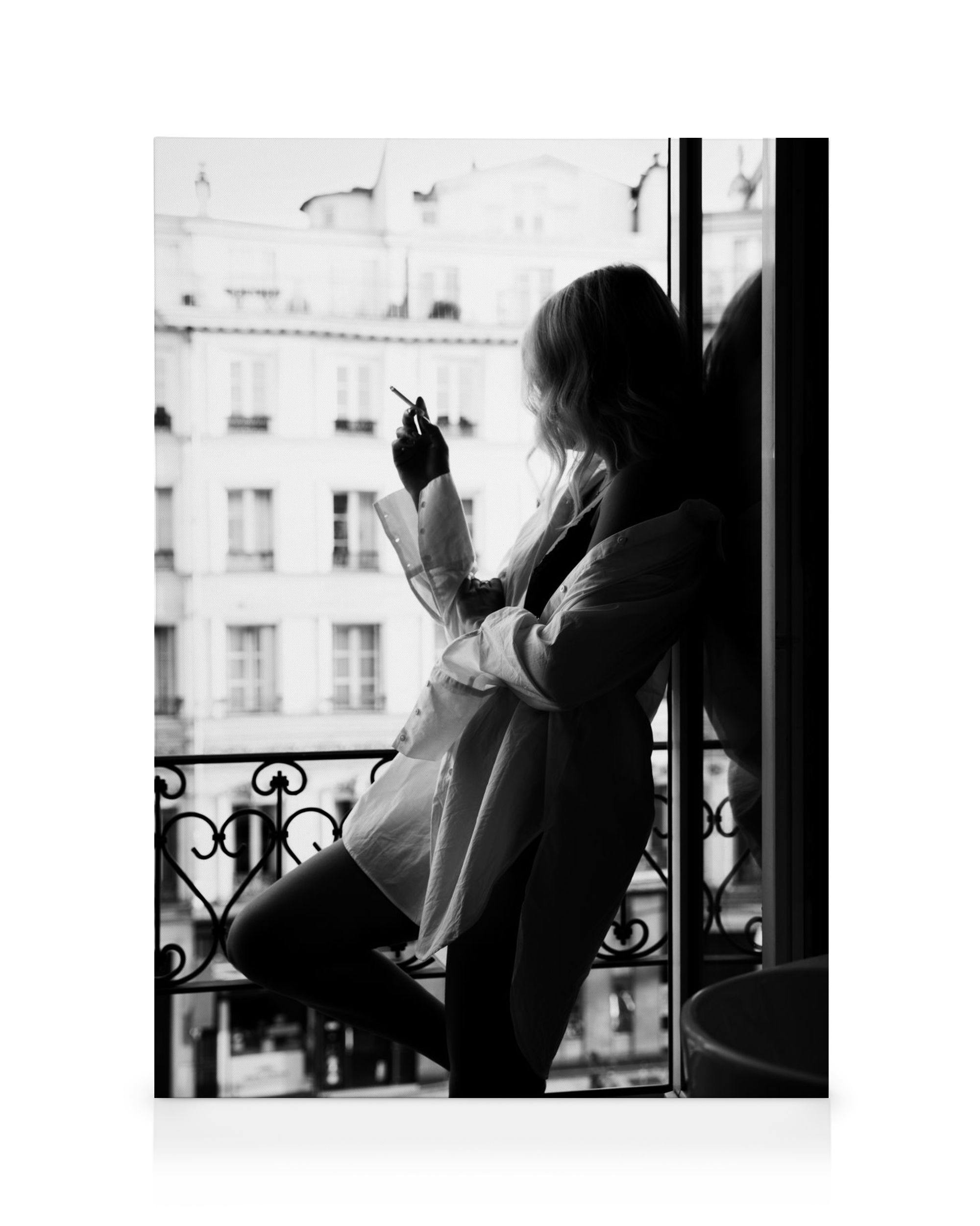 Toile noir et blanc dune personne assise près dune fenêtre, tenant une cigarette, avec des bâtiments en arrière-plan. typographi