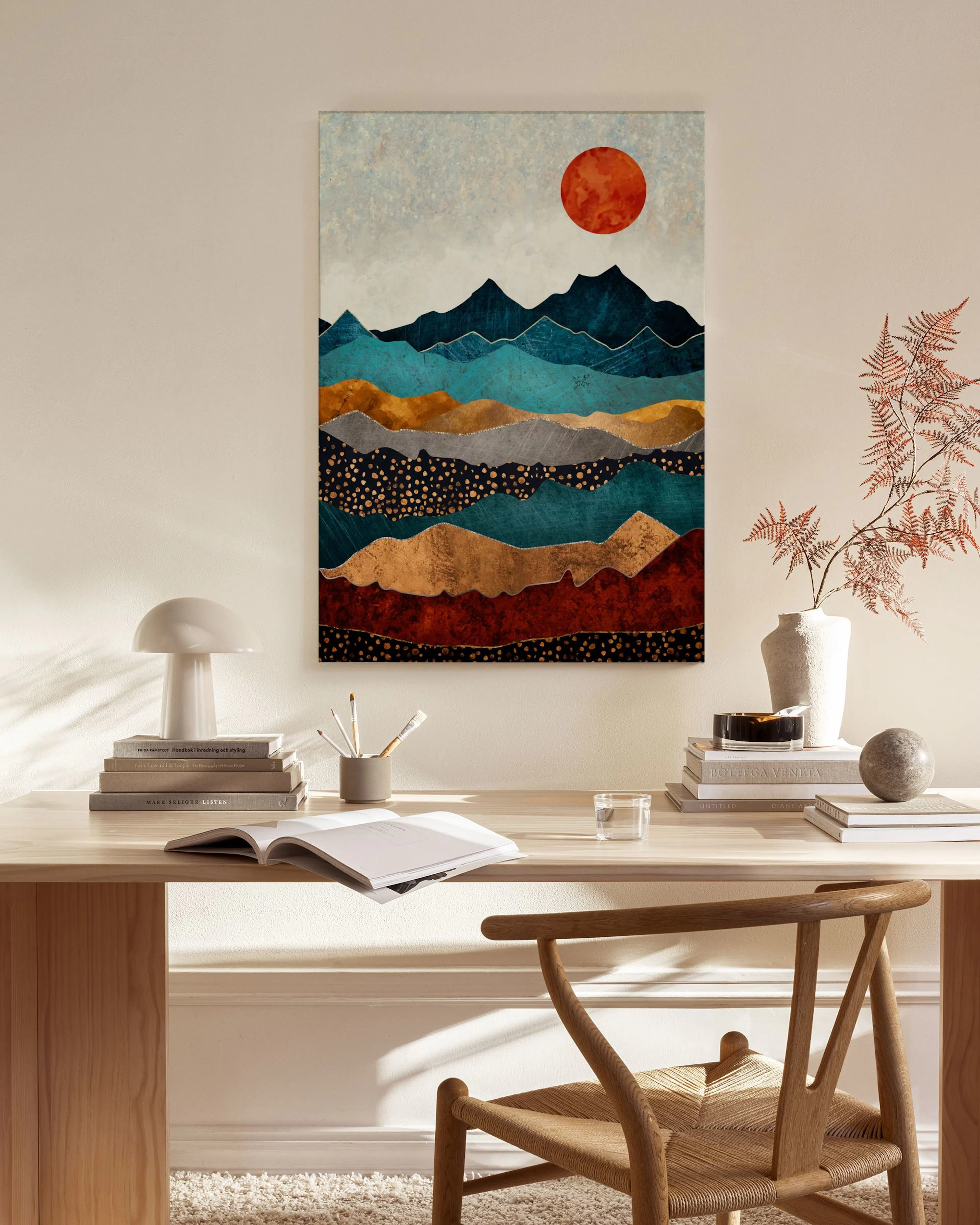Leinwandbild mit stilisierten Bergen in Blau- und Brauntönen sowie einem roten Mond, hängend in einem modern eingerichteten Wohn