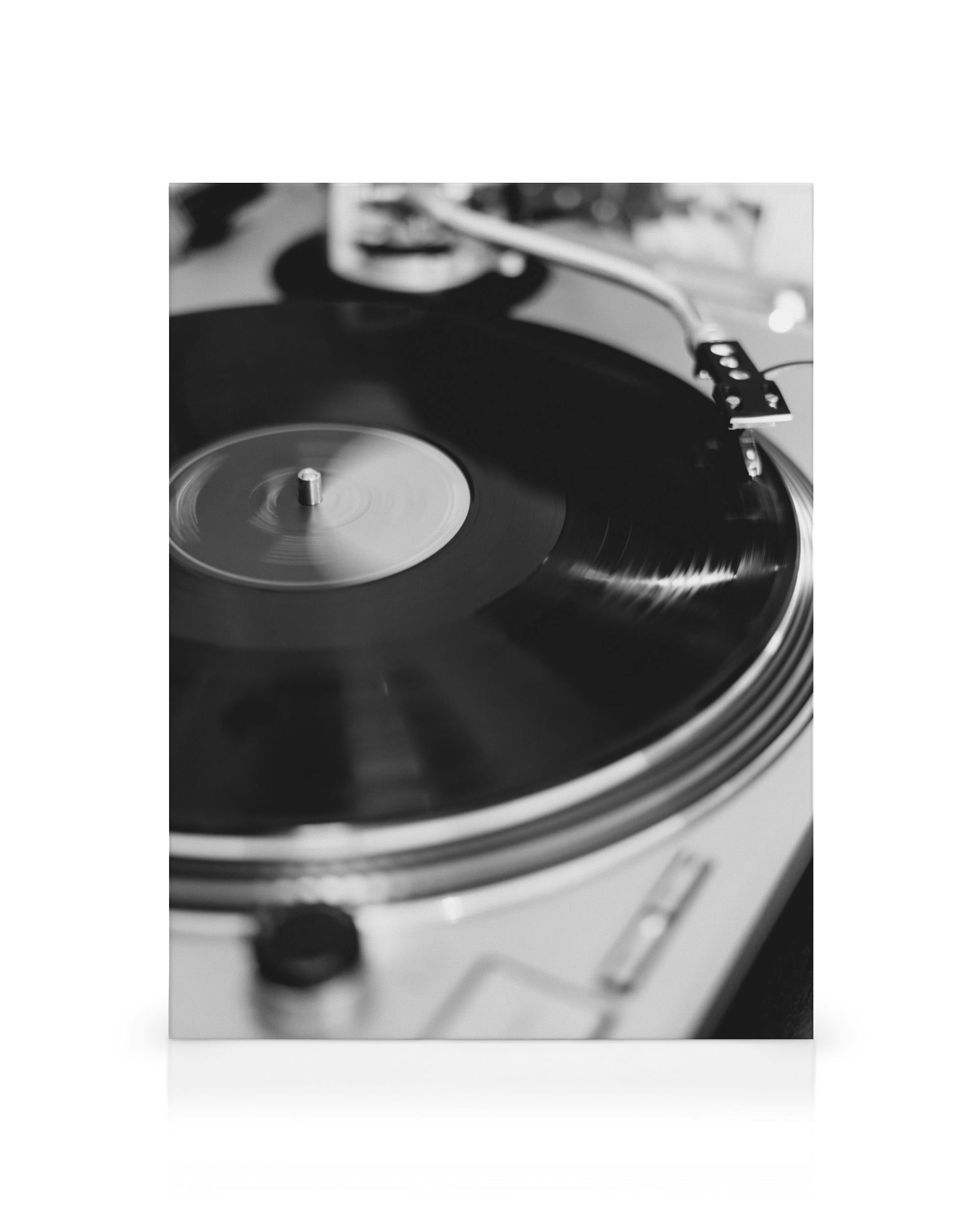 Black and white canvas print of a vinyl record spinning on a turntable, with the record and tonearm in sharp focus.