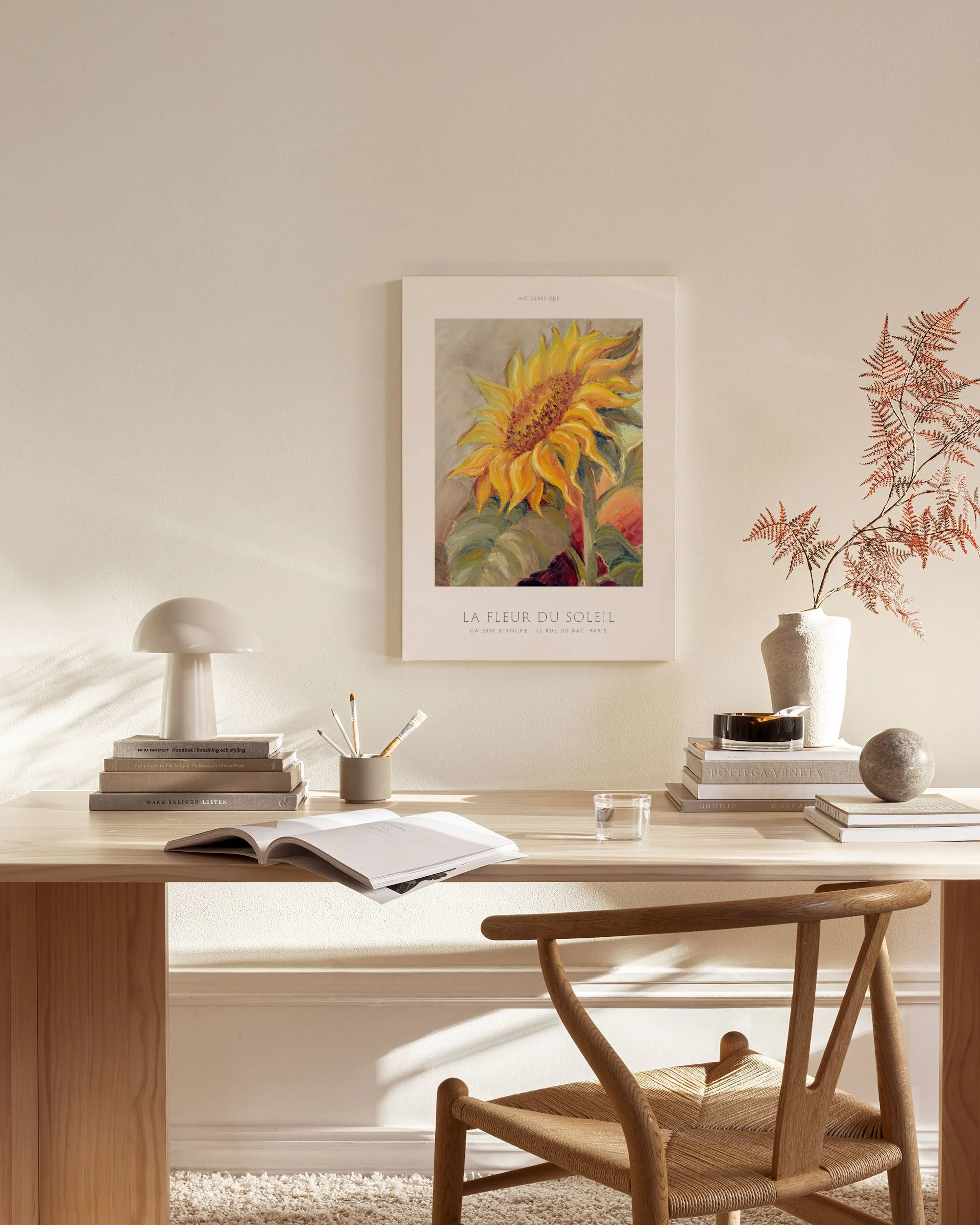 Sunflower canvas print with yellow petals and green leaves, hanging in a bright, minimalist living room above a wooden console.