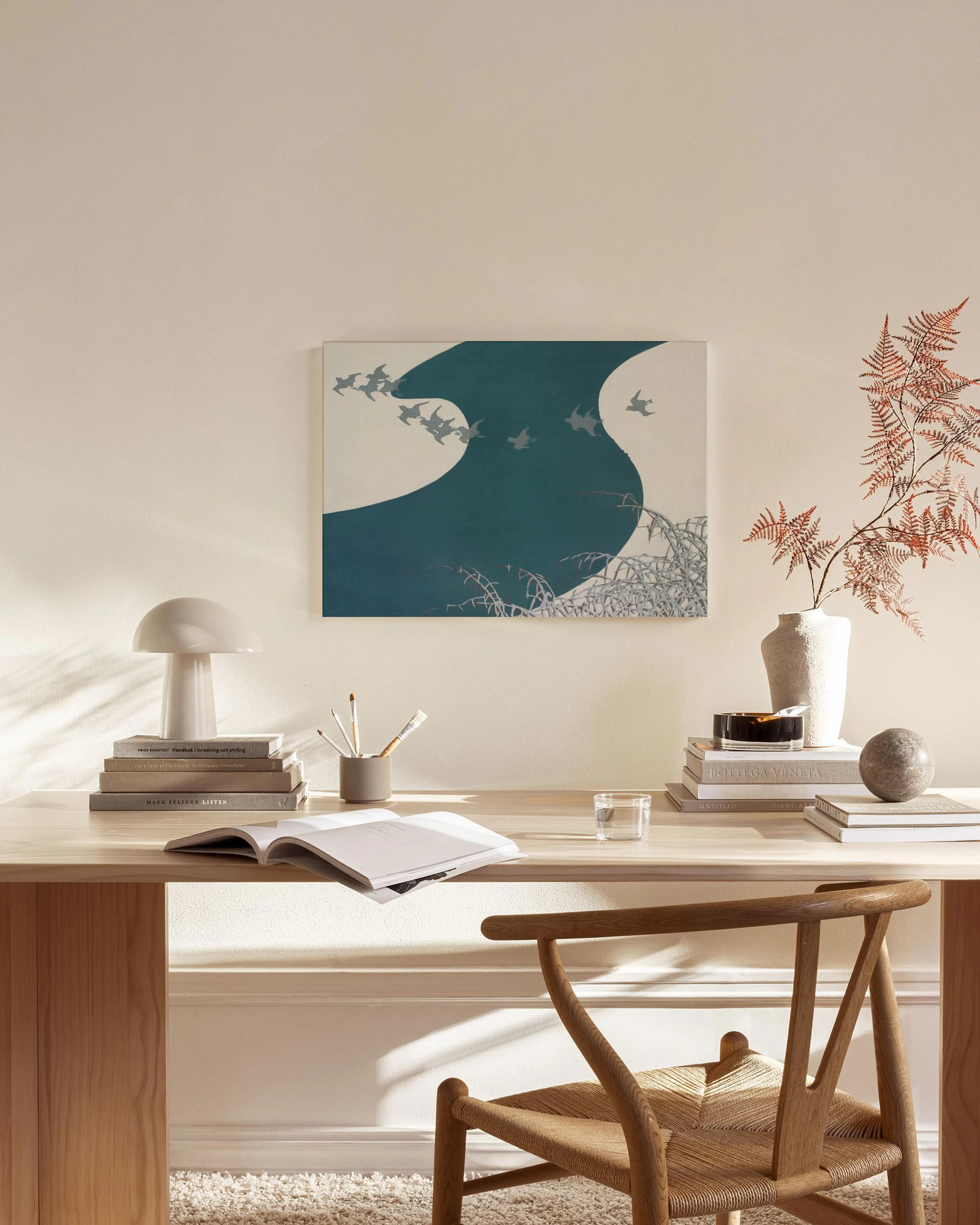 A canvas print of a flock of birds flying over a dark teal, wavy river, displayed in a minimal living room.