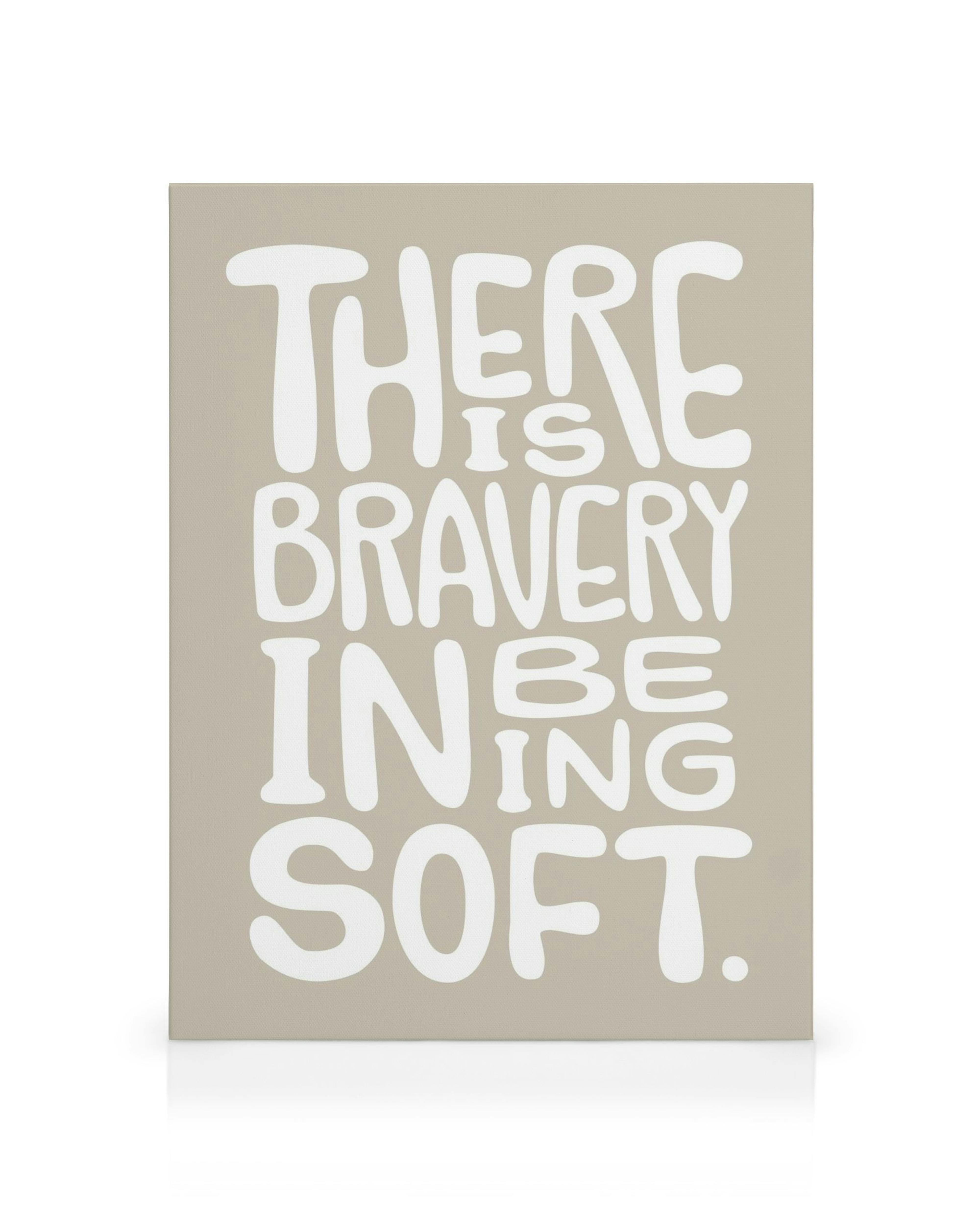 White text There Is Bravery In Being Soft on a grey canvas, with large, curved letters.