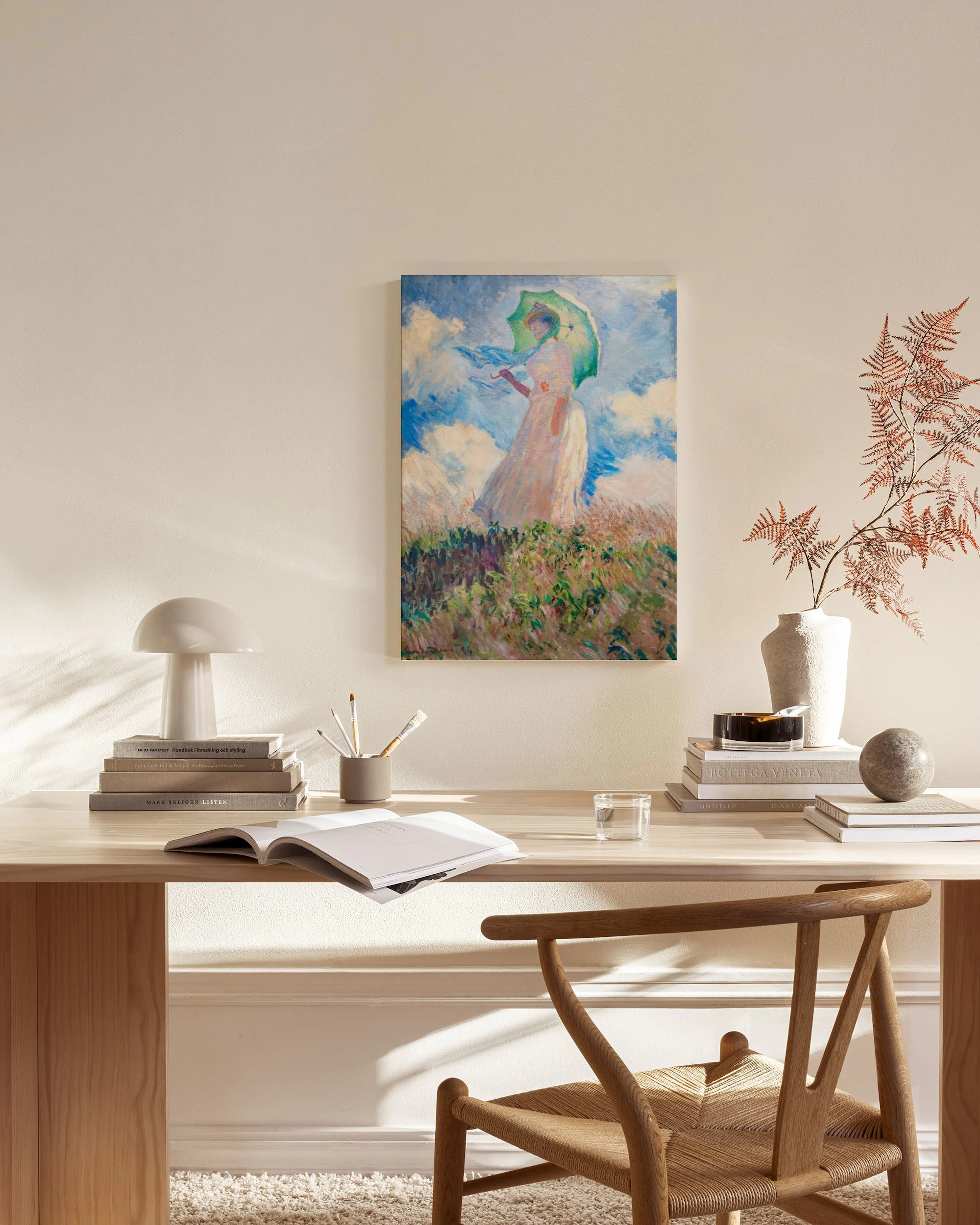 Canvas van een vrouw met een parasol op een heuvel, hangend in een modern interieur boven een dressoir.