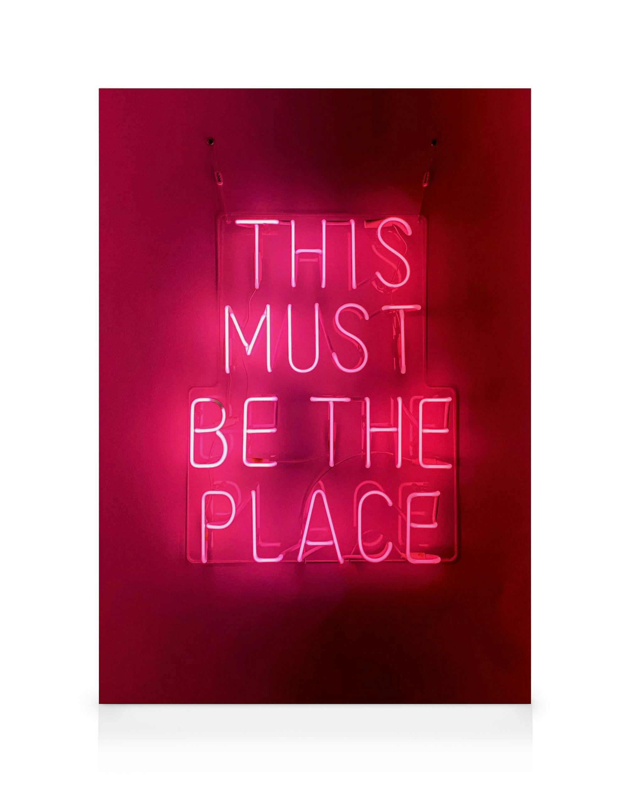 Canvastavla med neonskylt som säger This Must Be The Place i starkt rosa mot mörkrosa bakgrund. Väggkonst.