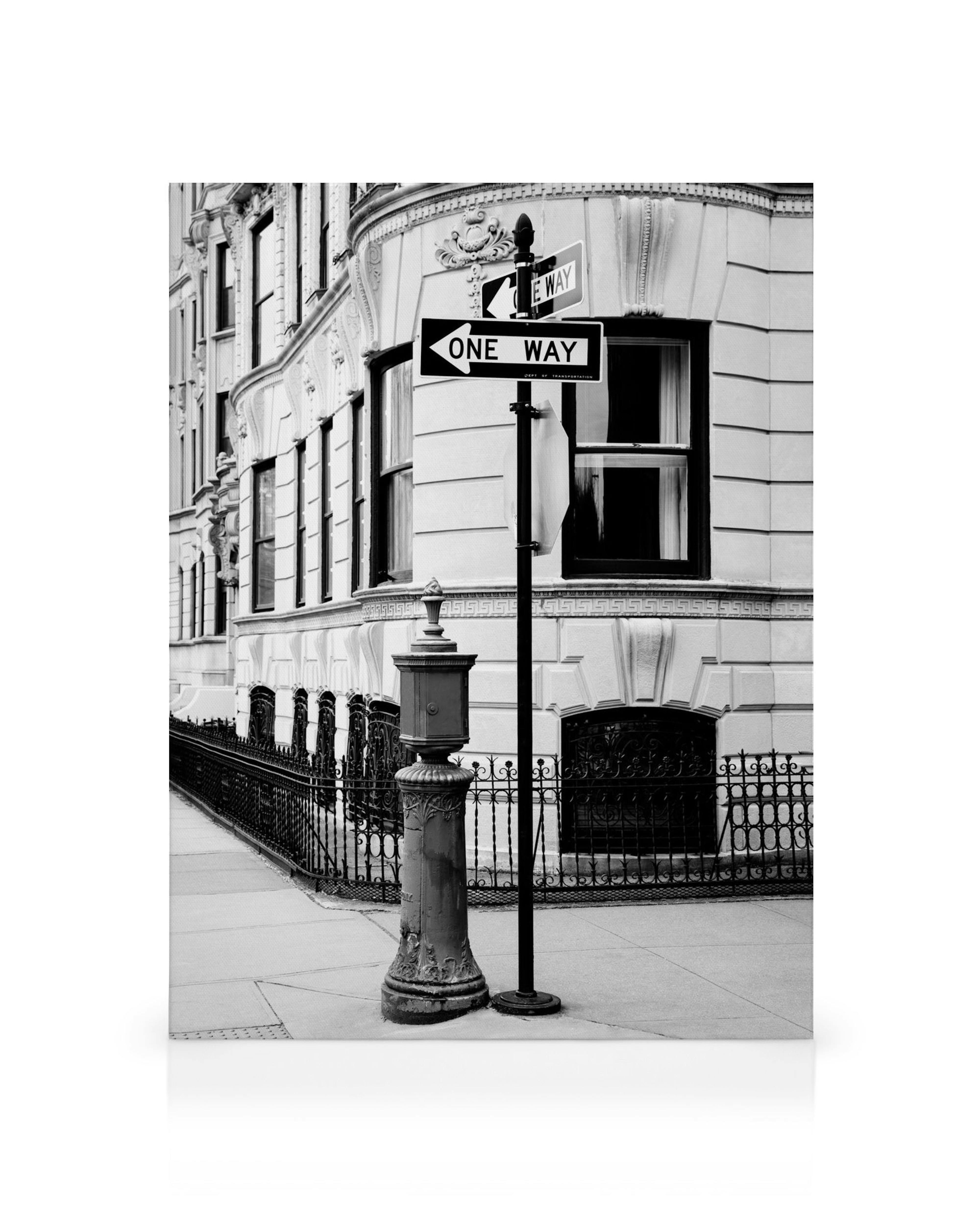 Black and white cityscape canvas print featuring a street corner with a one-way sign, fire hydrant, and ornate building.