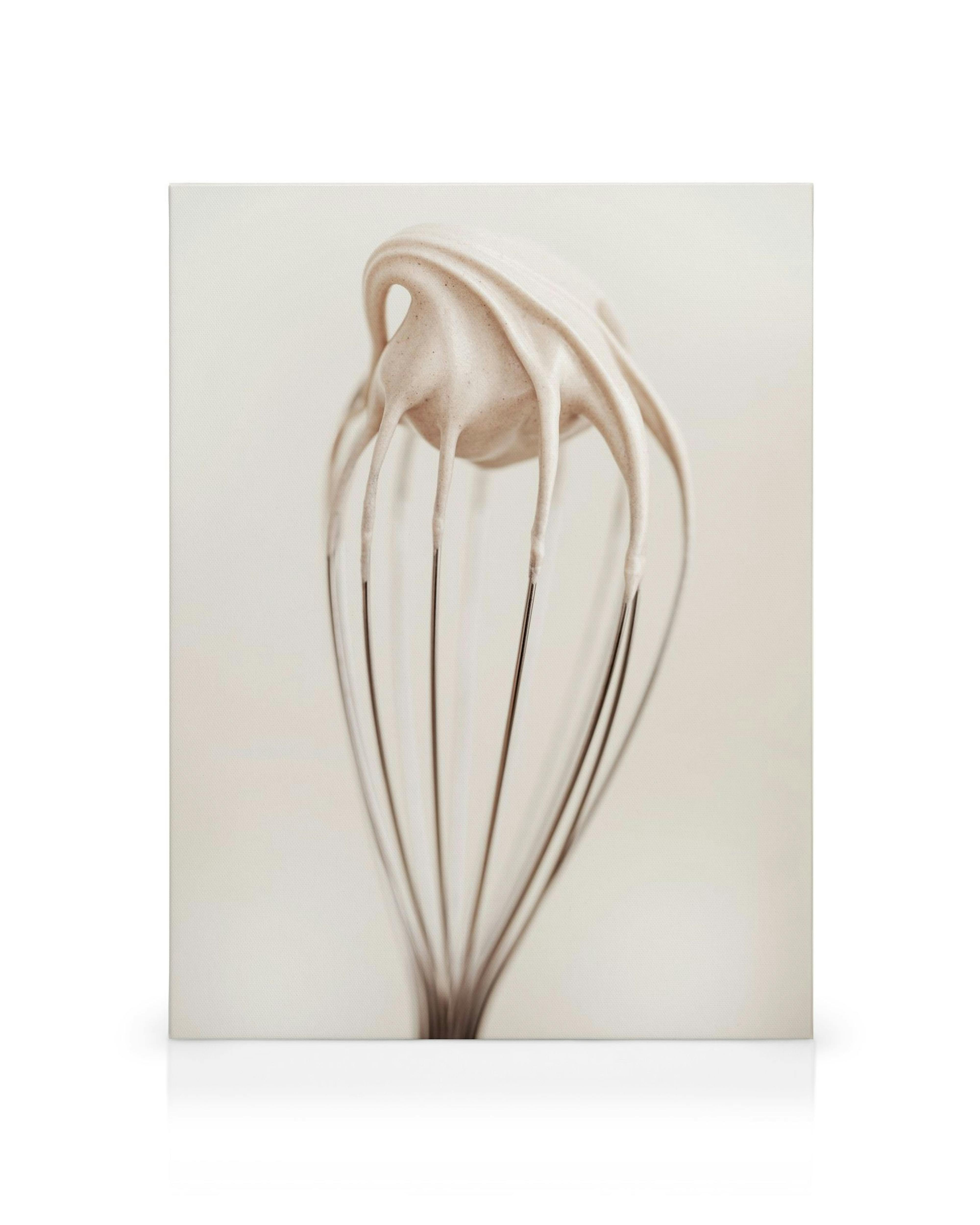 Lærred med en visp fuld af cremet topping, der drypper ned fra piskeriset.