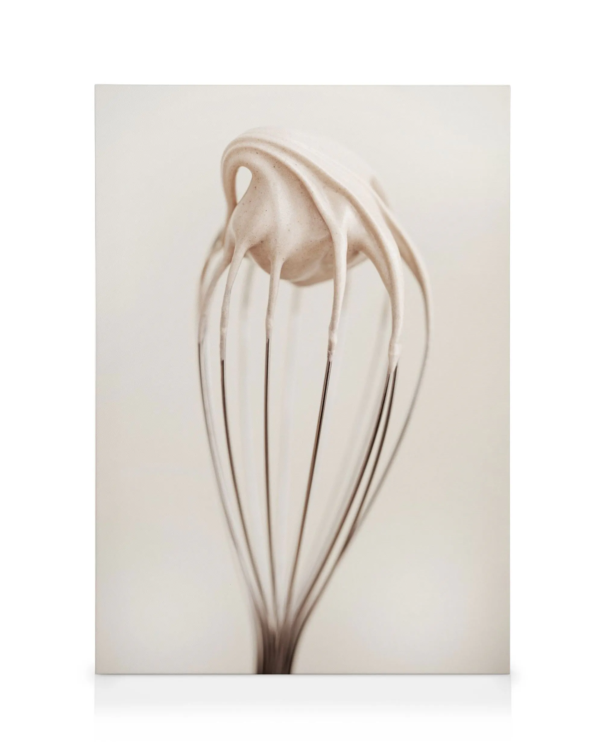 Canvas print of a whisk dripping with creamy white batter on a beige background