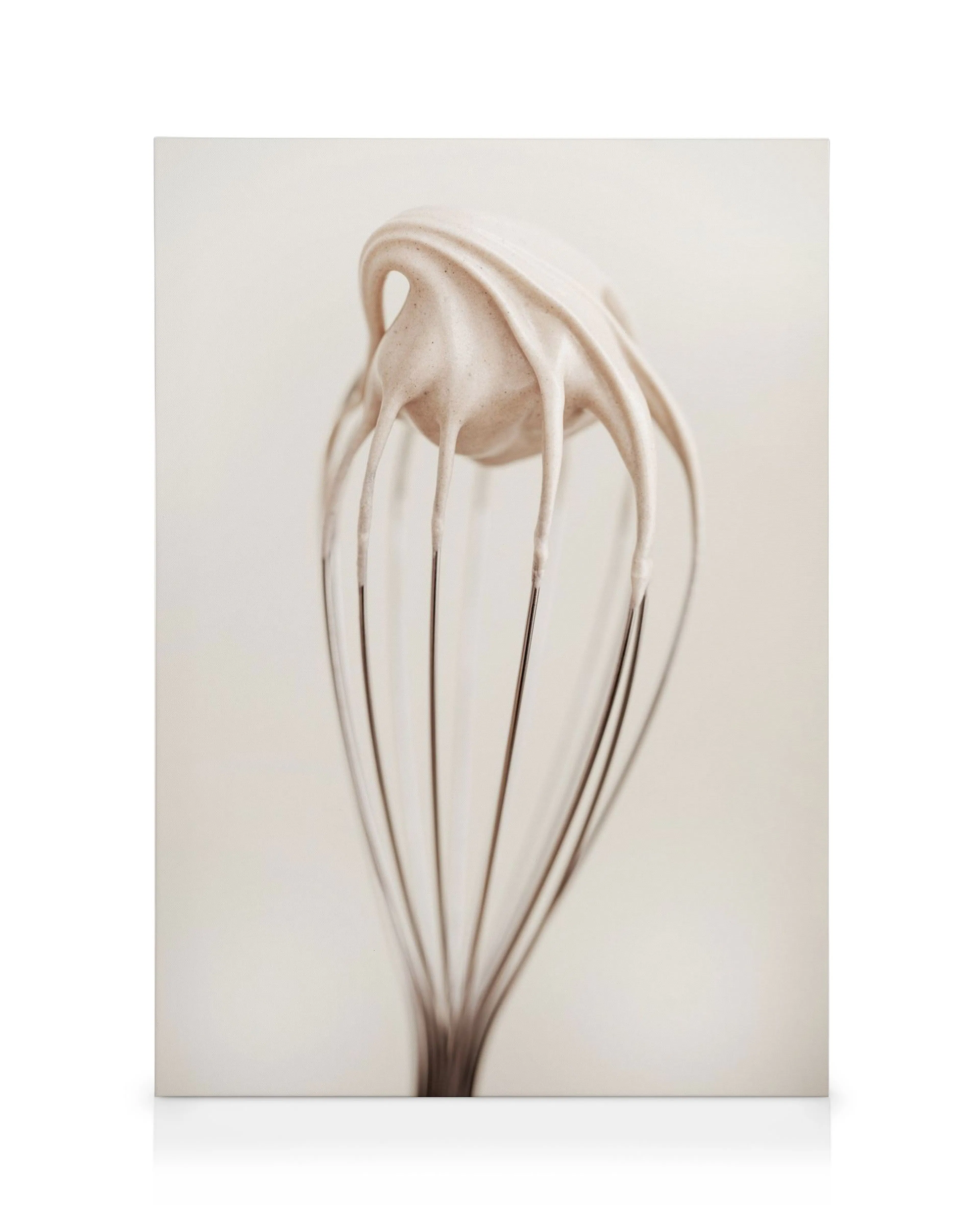 Canvas print of a whisk dripping with creamy white batter on a beige background