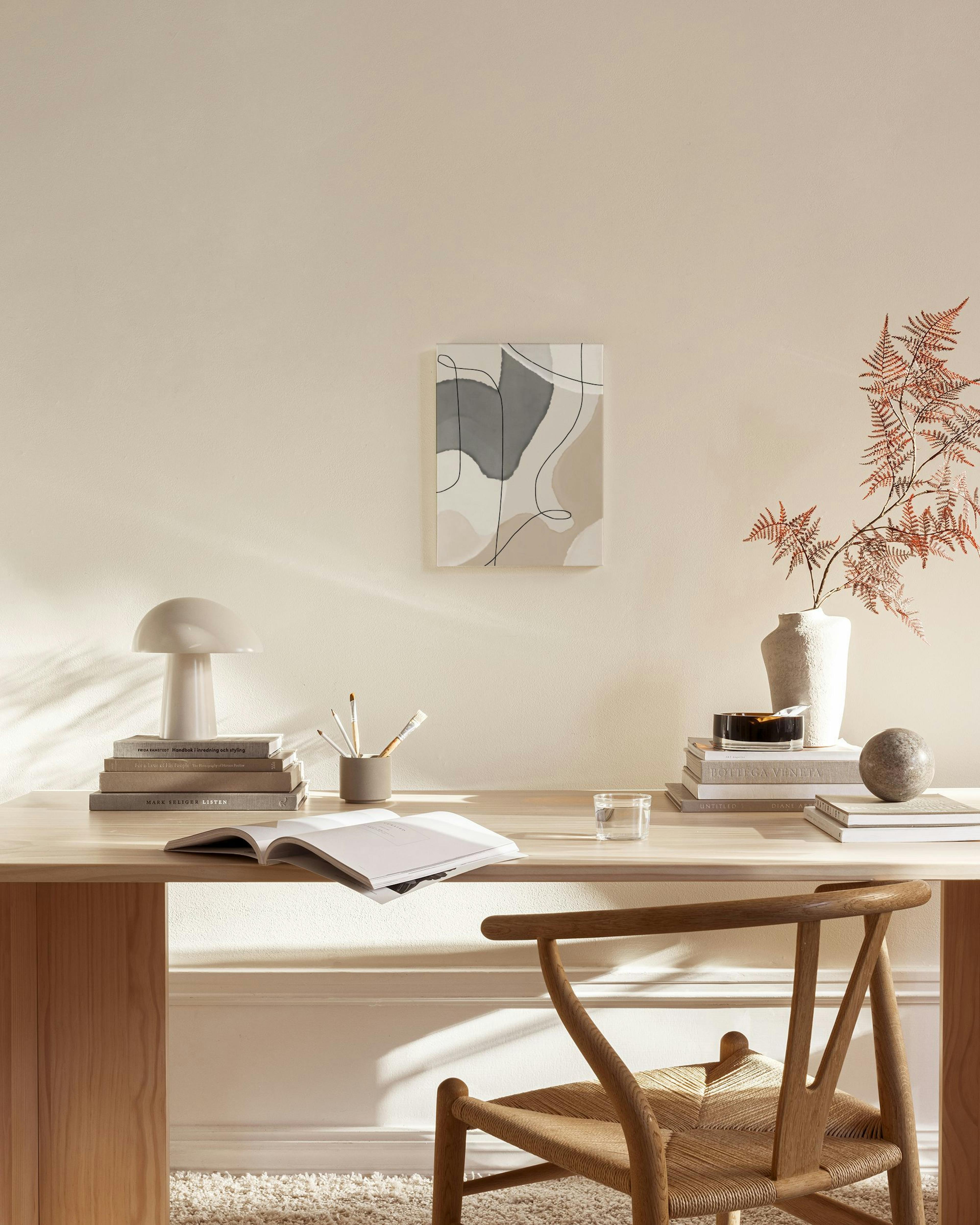 Abstraktes Leinwandbild mit organischen Formen in Grau und Beige, mit schwarzen und weißen Linien, in einem modernen Wohnzimmer.