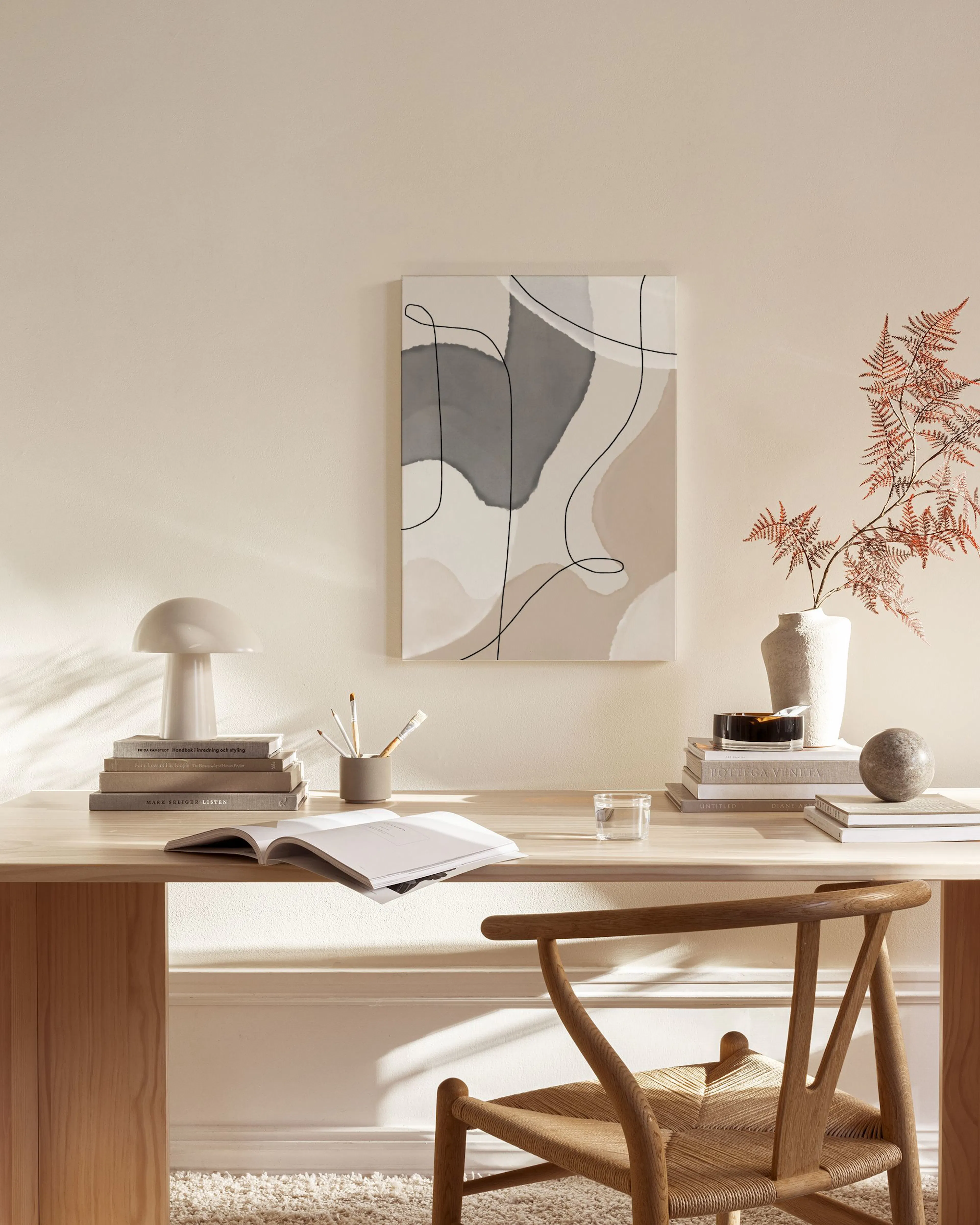Leinwandbild mit abstrakten Formen in Beige, Grau und Weiß, durchzogen von schwarzen Linien, hängt über einem Sideboard in einem