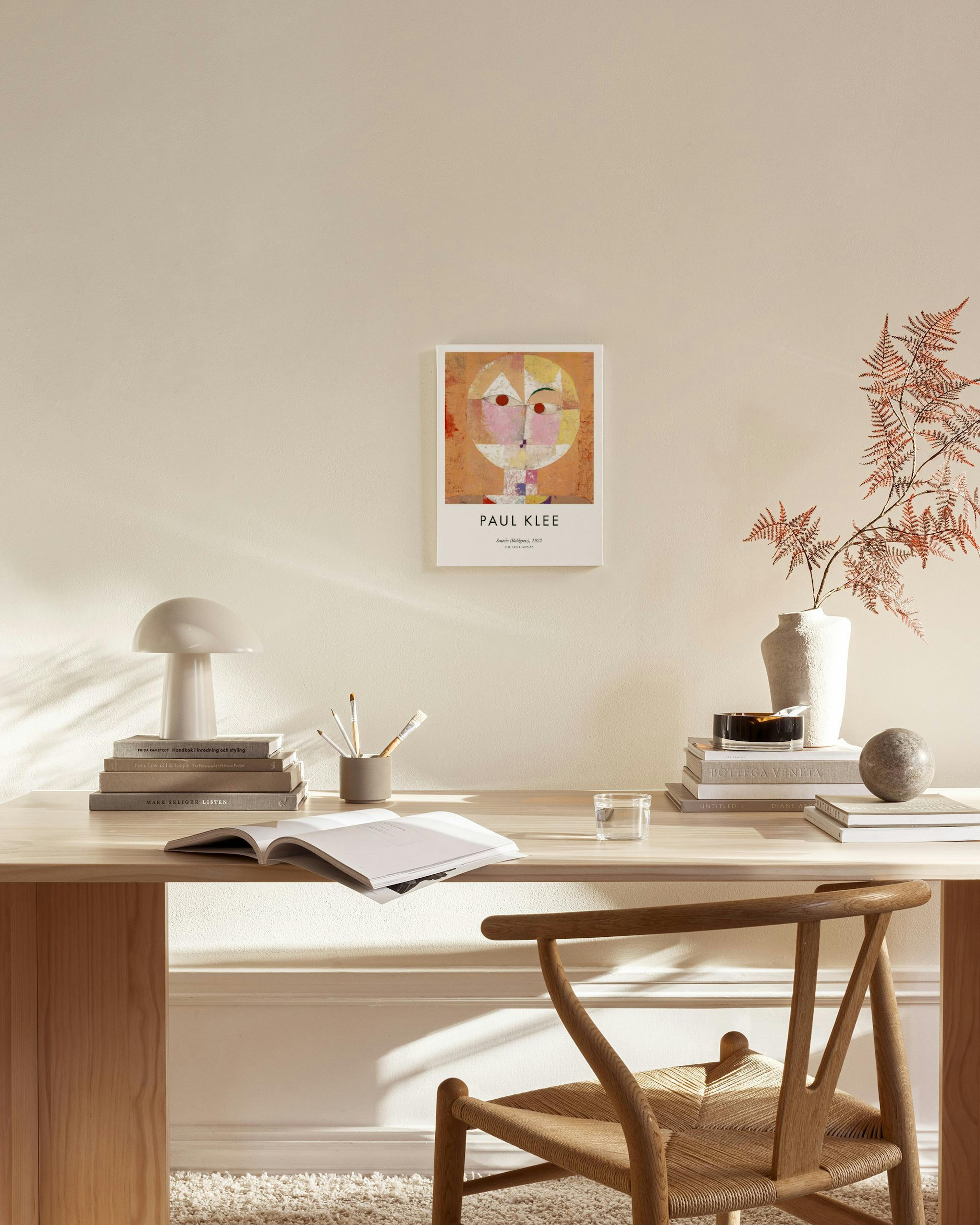 A colorful Paul Klee art print featuring a geometric face, displayed in a bright living room above a wooden console.