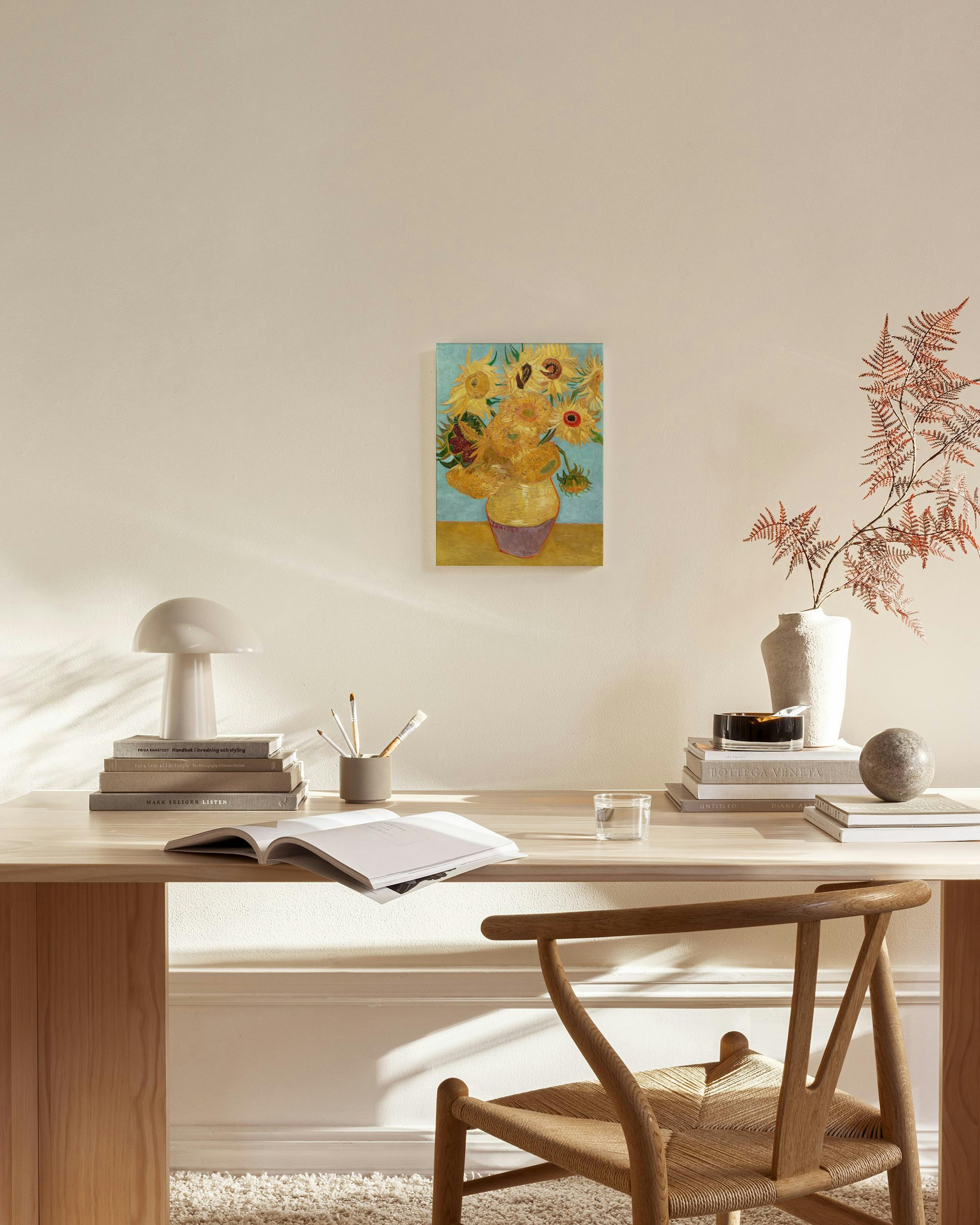 A canvas print of Van Goghs Sunflowers in a vase, hanging in a modern living room above a wooden console table.