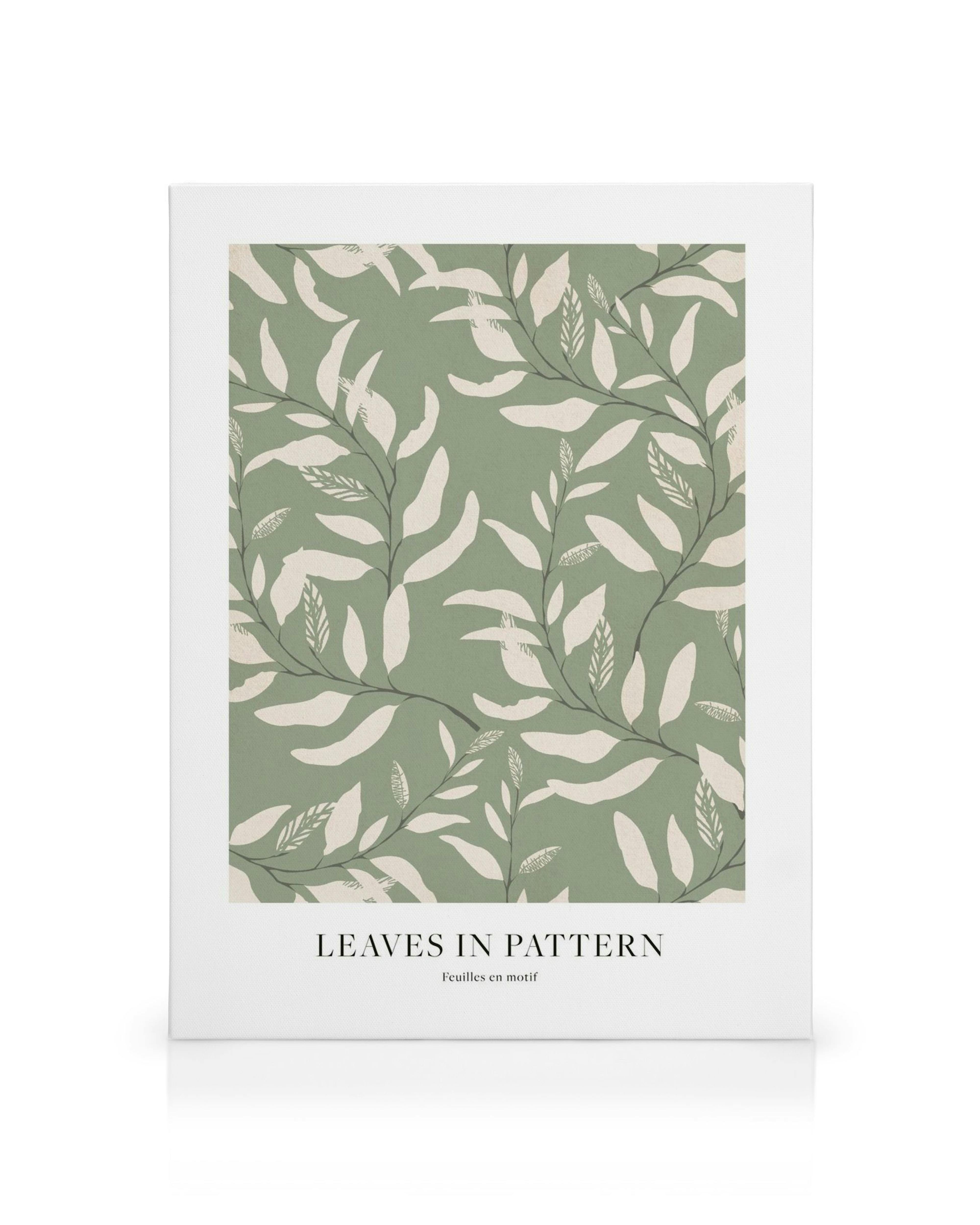 Plátno s opakujúcim sa vzorom svetlých listov na zelenošedom pozadí, doplnené nápisom Leaves in Pattern
