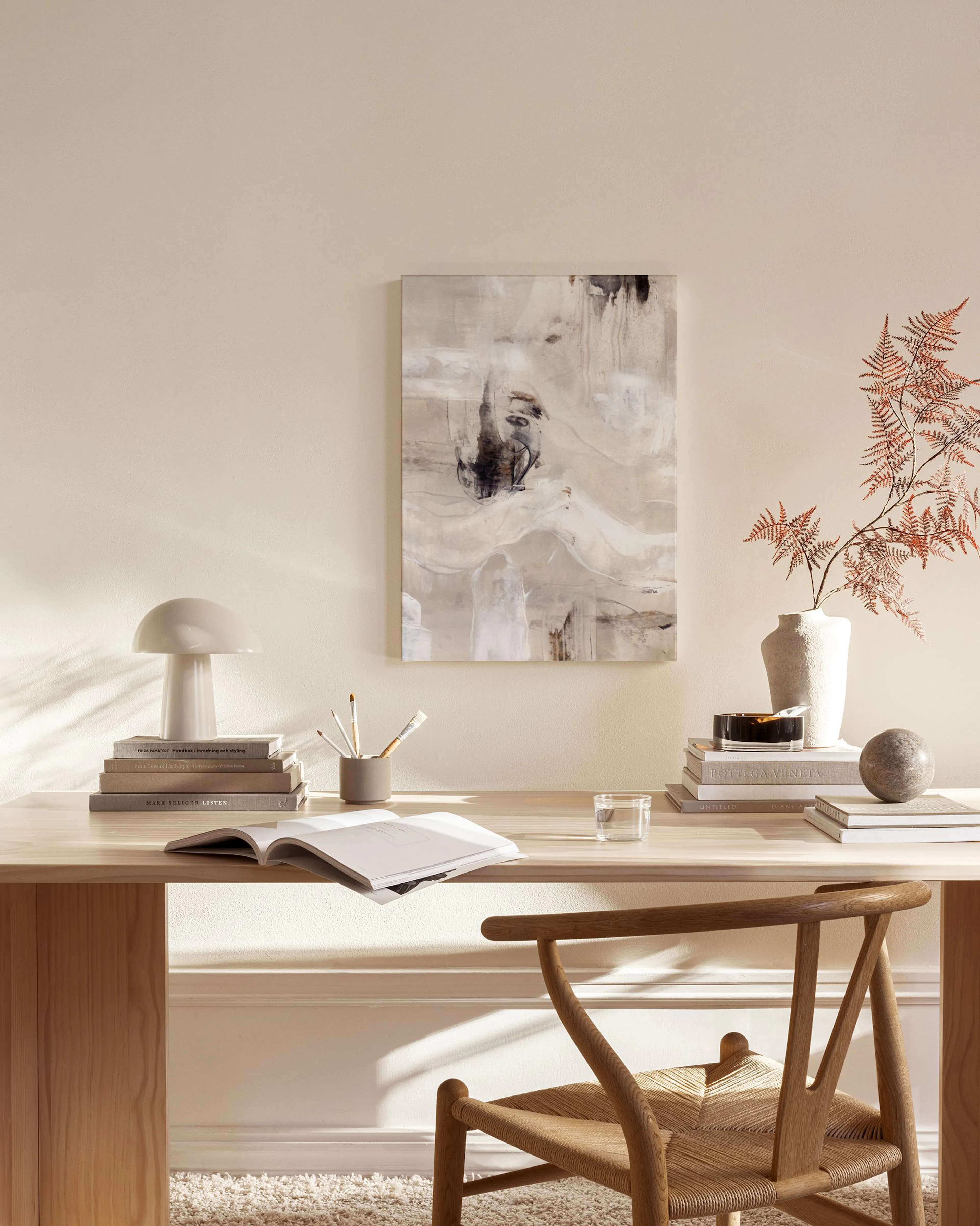 An abstract canvas print with organic flowing shapes in beige, white, and black, hanging in a minimalist living room.