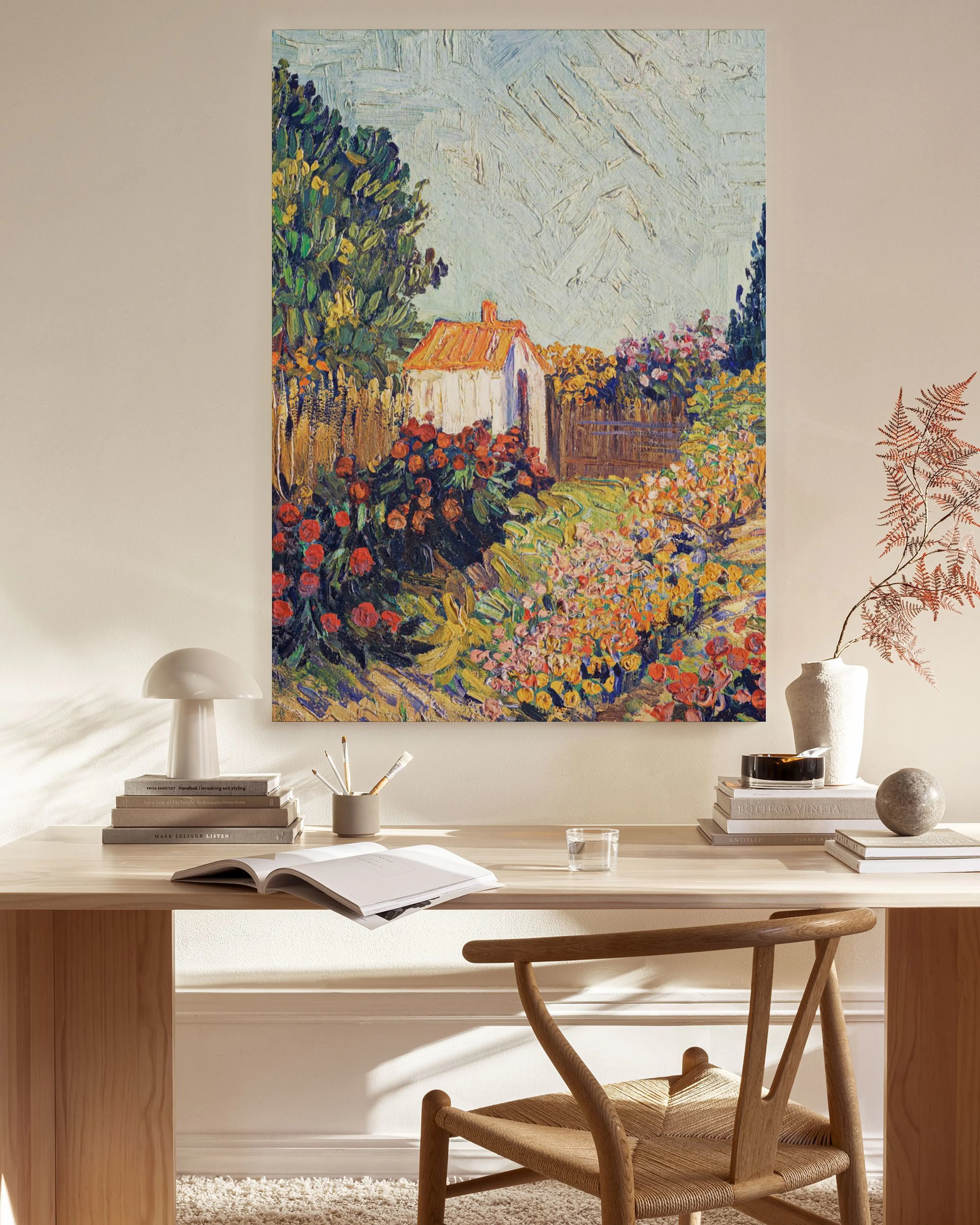 A vibrant canvas print of a garden path with a white house and colorful flowers, displayed in a bright, modern living room.