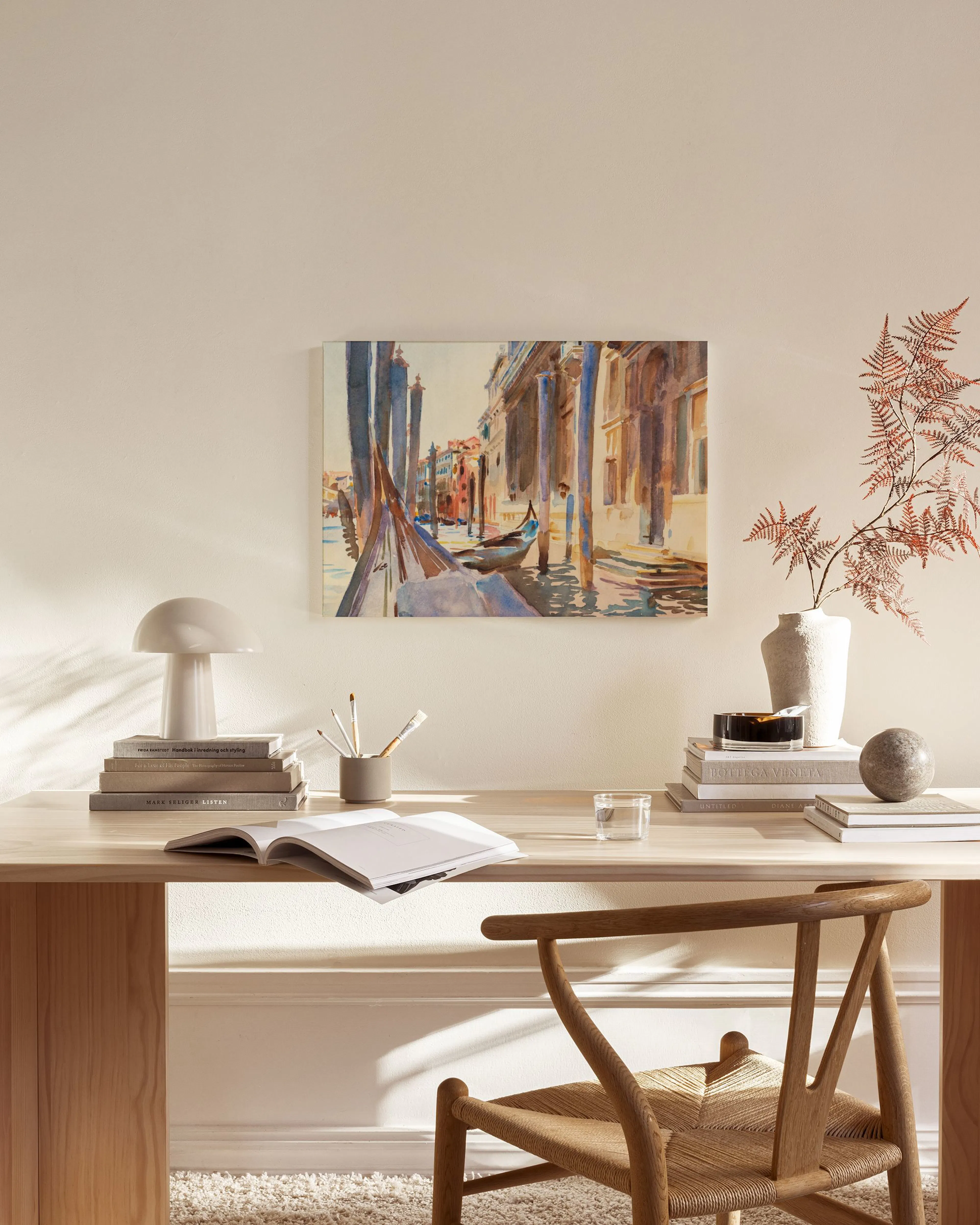 Stampa su tela di un canale veneziano con gondola, appesa in un soggiorno moderno sopra una panca in legno.