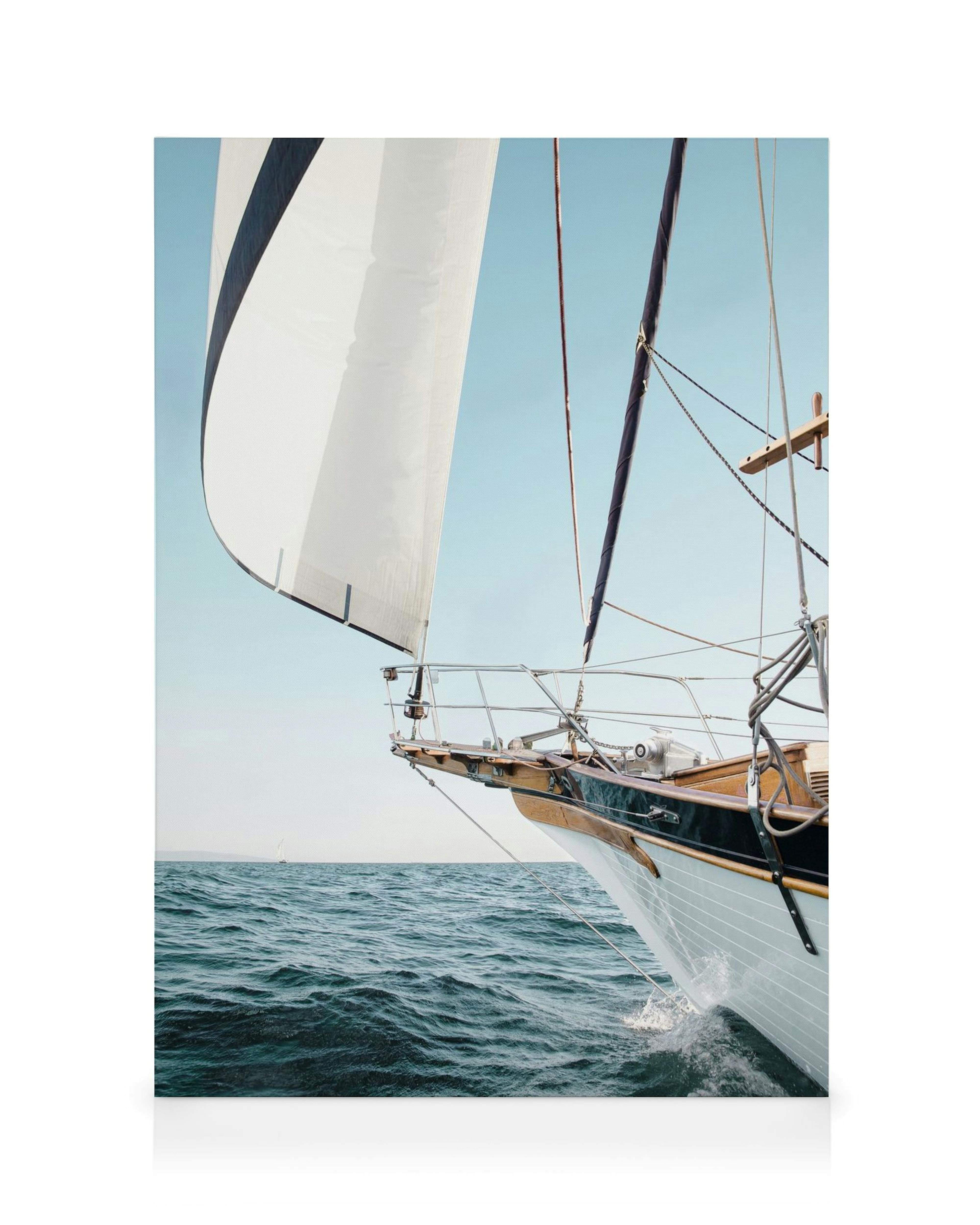 Seilbåt på åpent hav i blått og beige, med hvitt seil og trekantet skrog. Vanndråper spruter fra baugen.