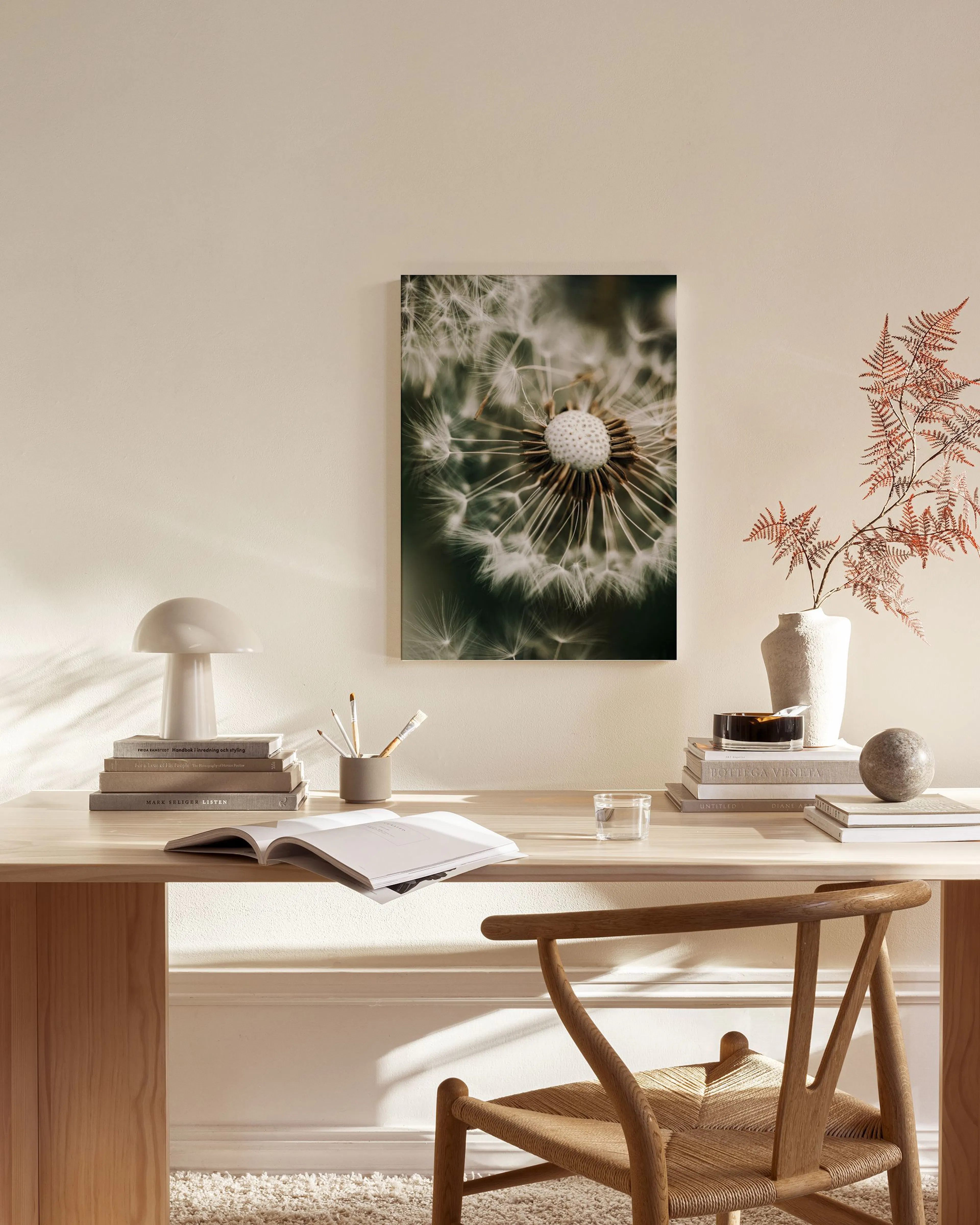 Stampa su tela di un dente di leone in primo piano, appesa in un soggiorno moderno sopra una credenza in legno.