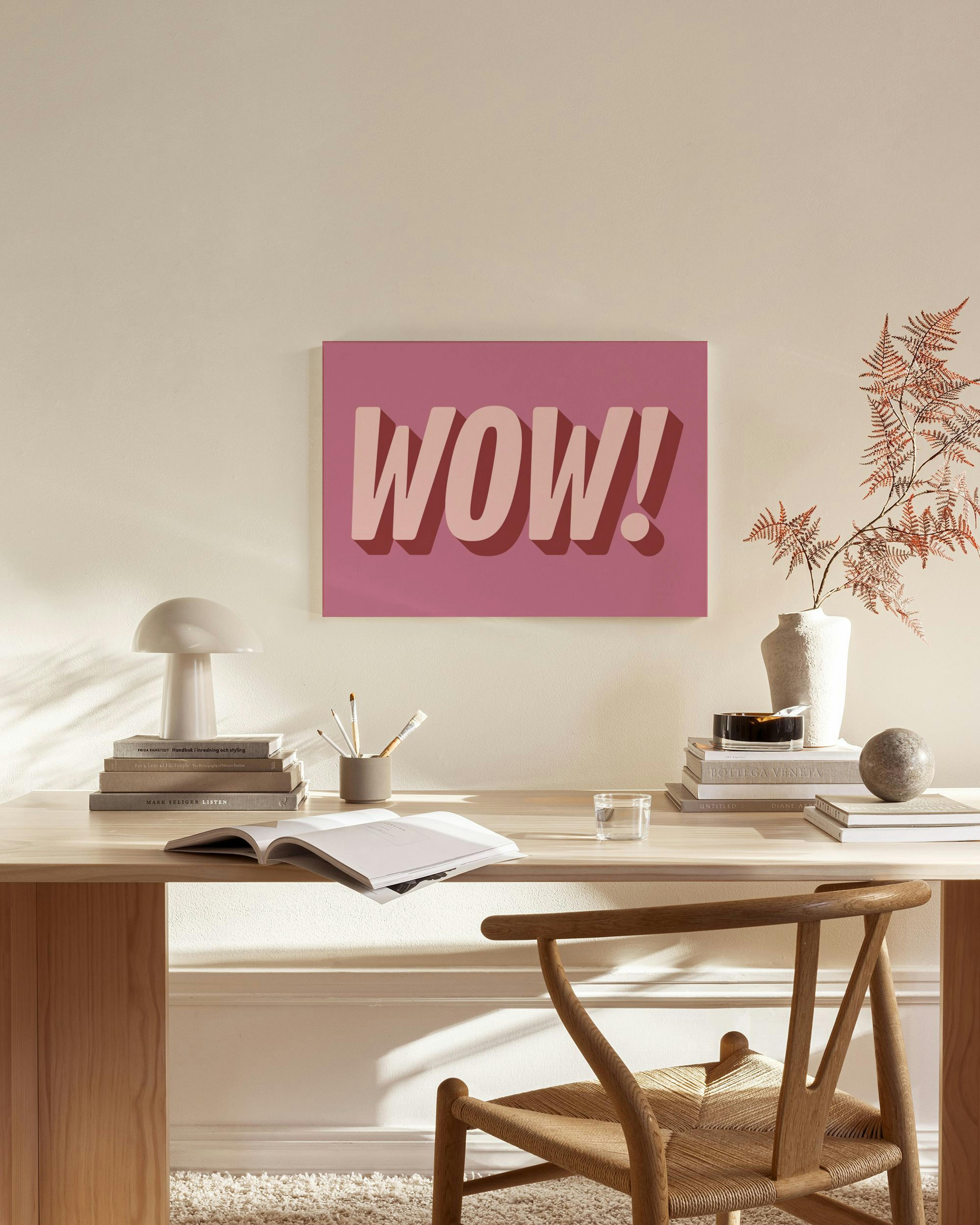 Canvas met roze WOW! tekst in 3D-stijl, hangend boven een houten dressoir in een lichte woonkamer.