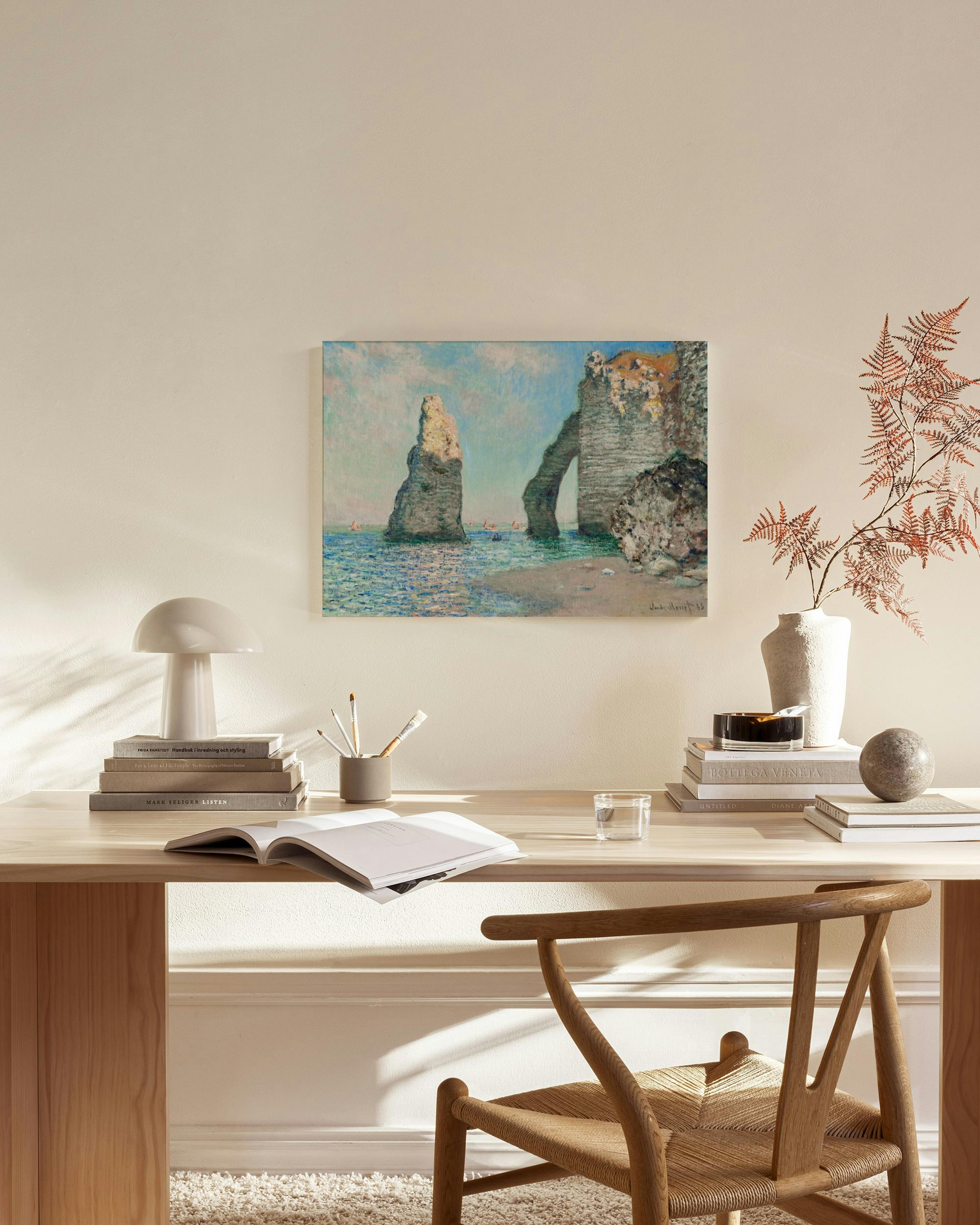 Leinwandbild mit Meereslandschaft von Étretat, hängt über einem Holzregal in einem hellen Wohnzimmer.