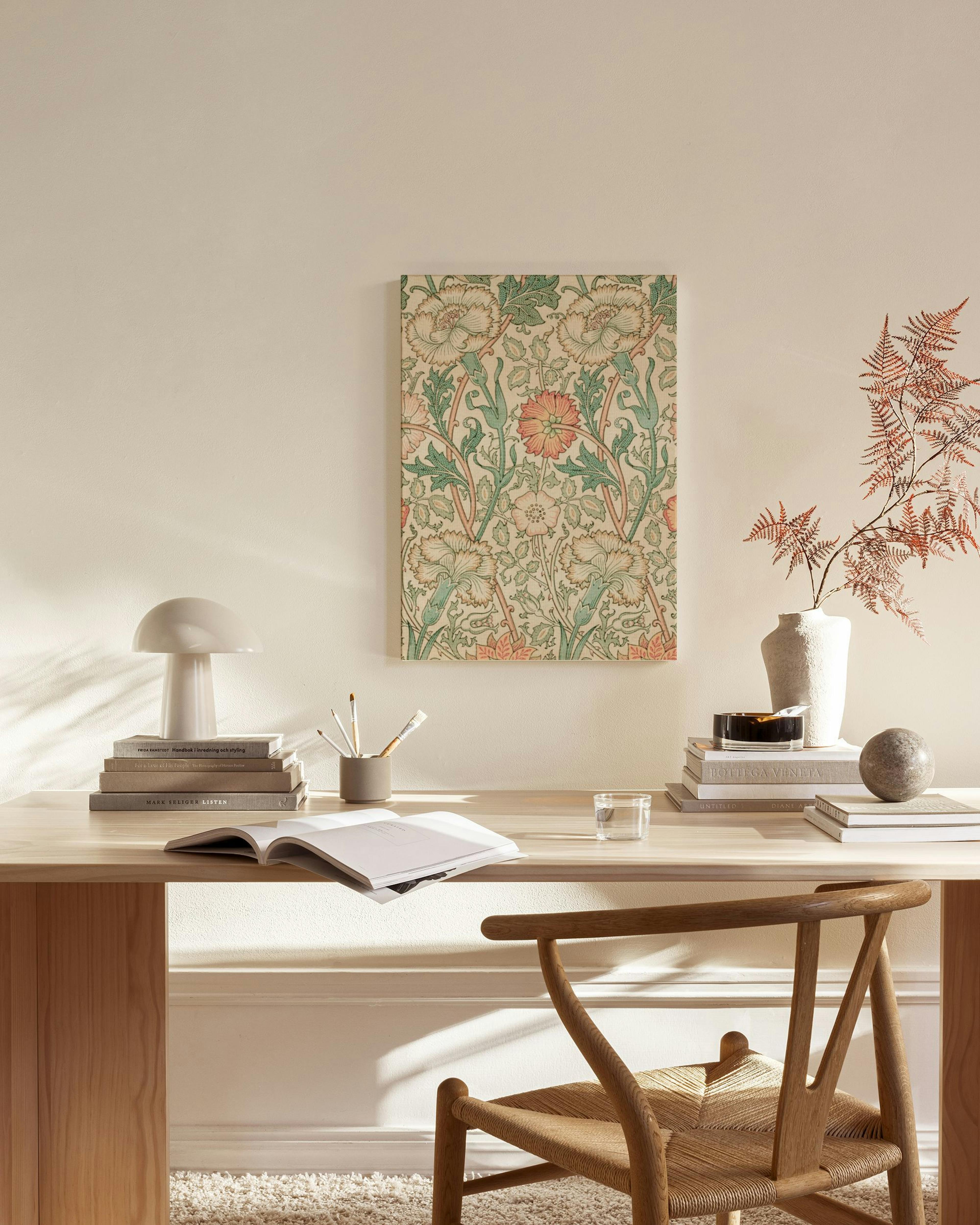 Toile murale au motif floral vert et rose saumon, suspendue dans un salon moderne aux tons neutres.