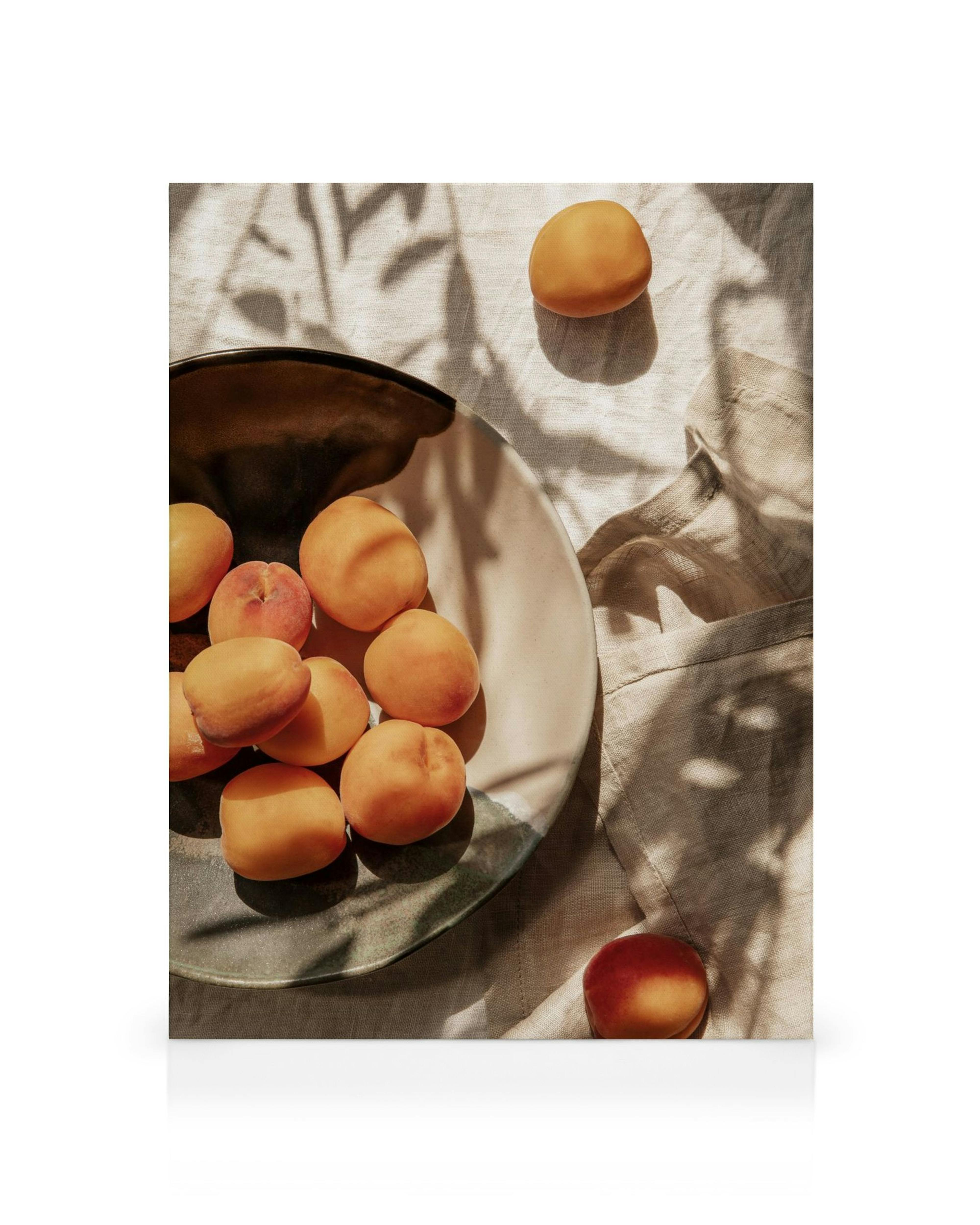 Pfirsiche in einer Schale auf Stoff mit Blätterschatten, sanftes Sonnenlicht, natürliches Stillleben