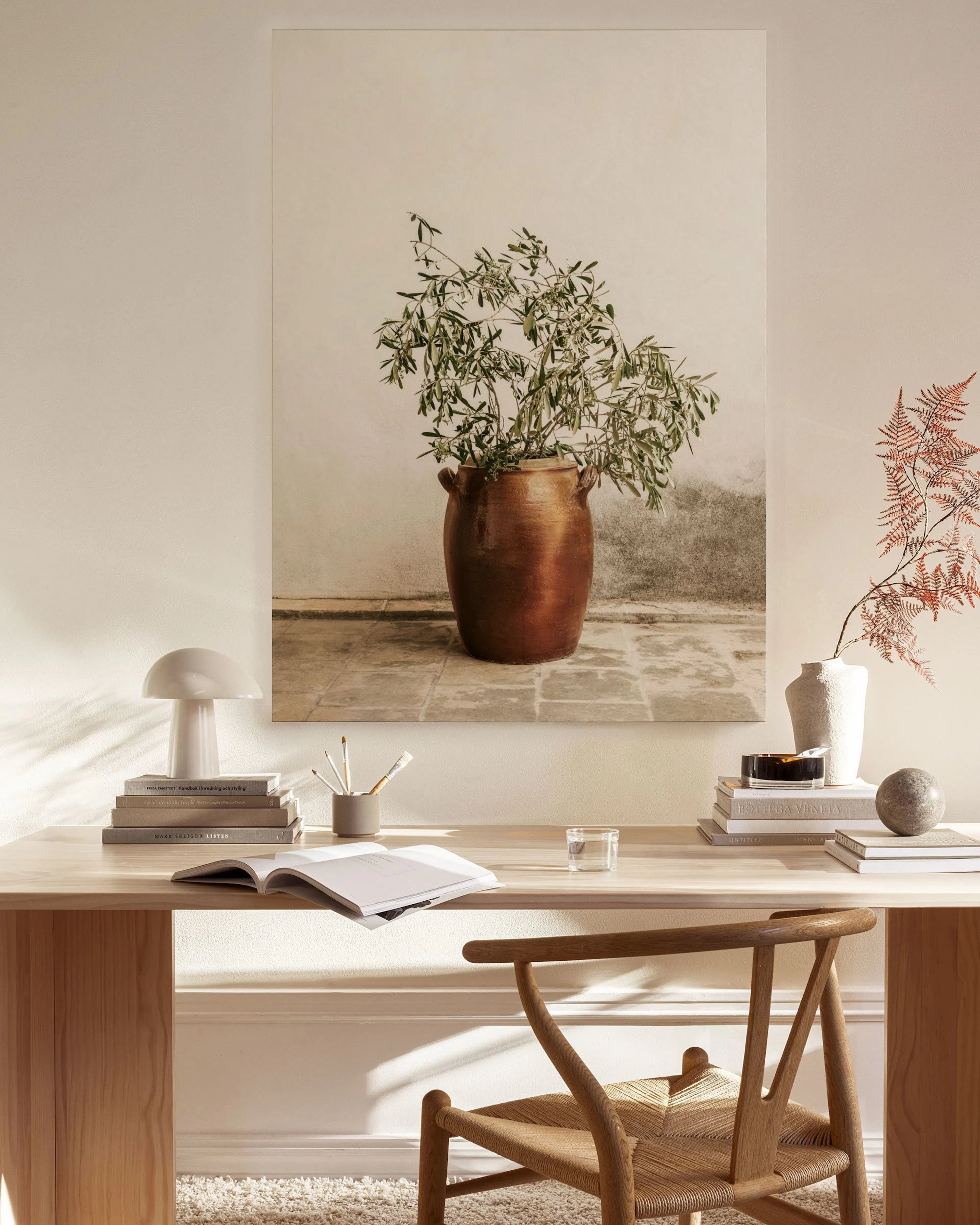 Toile murale, plante verte dans un pot en cuivre sur fond beige, au-dessus dun meuble bas dans un salon moderne.