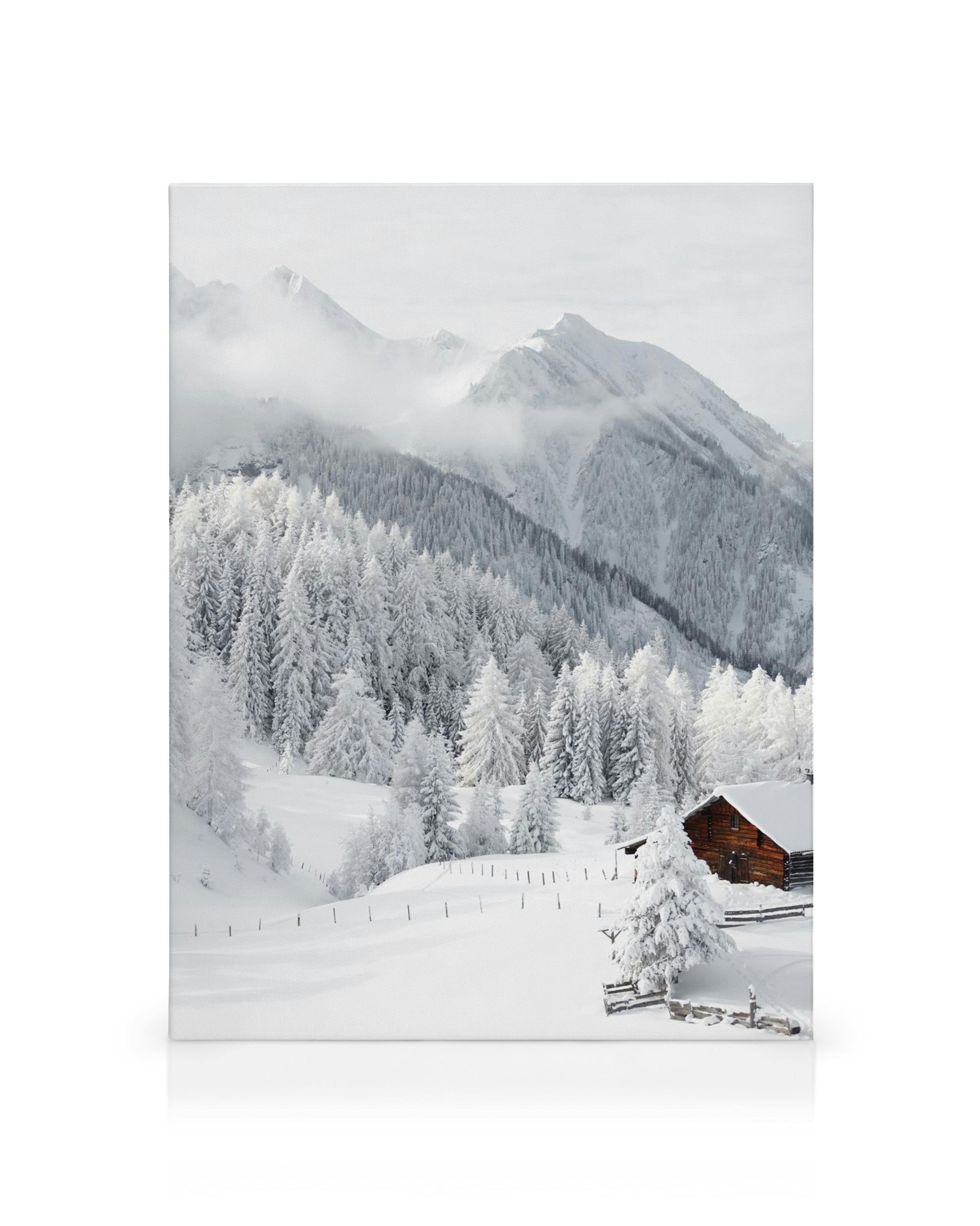 Toile paysage de montagne enneigé avec chalet en bois et forêt de sapins sous un ciel nuageux.