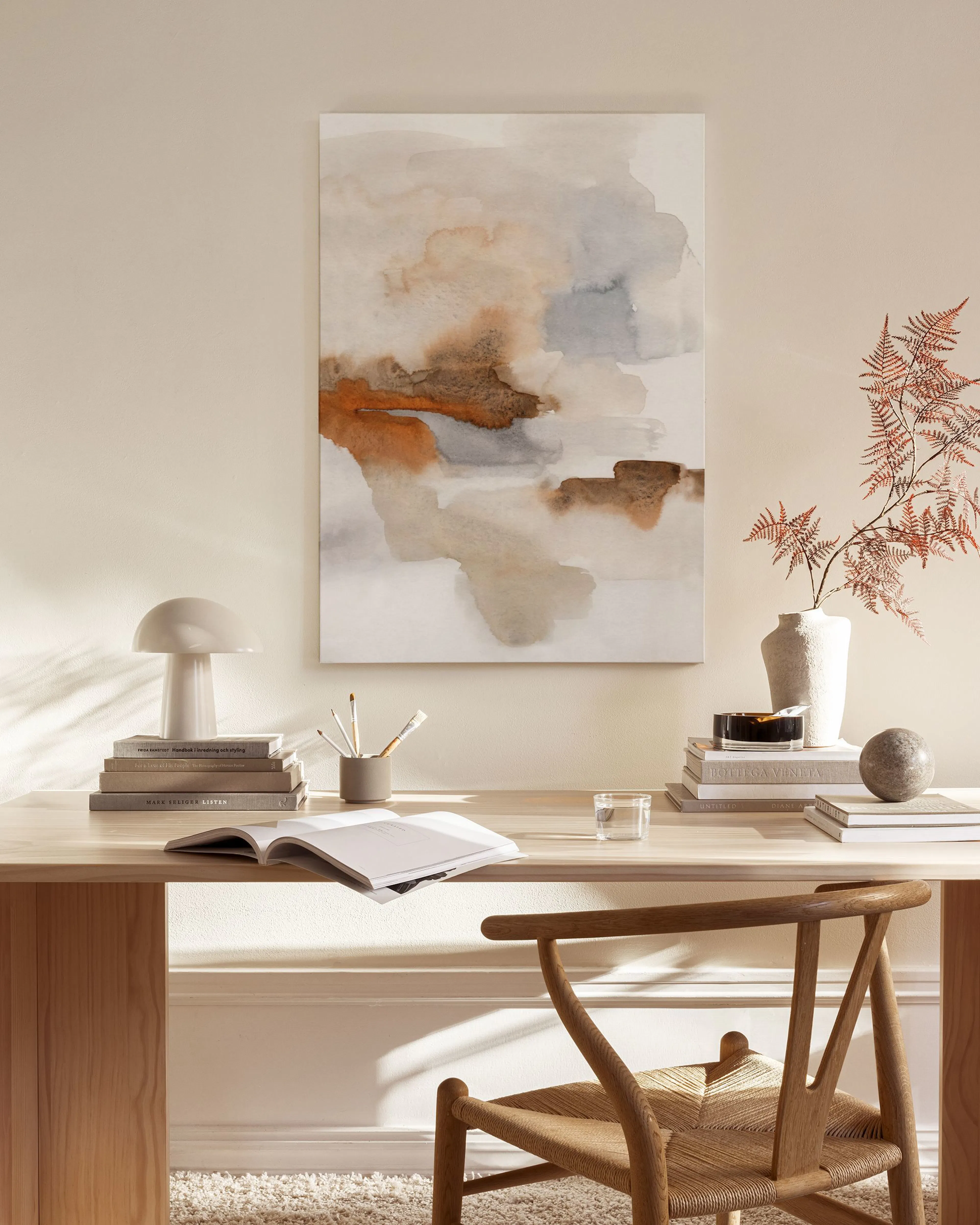 Een canvas met abstracte oranje, grijze en beige vormen, hangend boven een houten dressoir in een woonkamer.