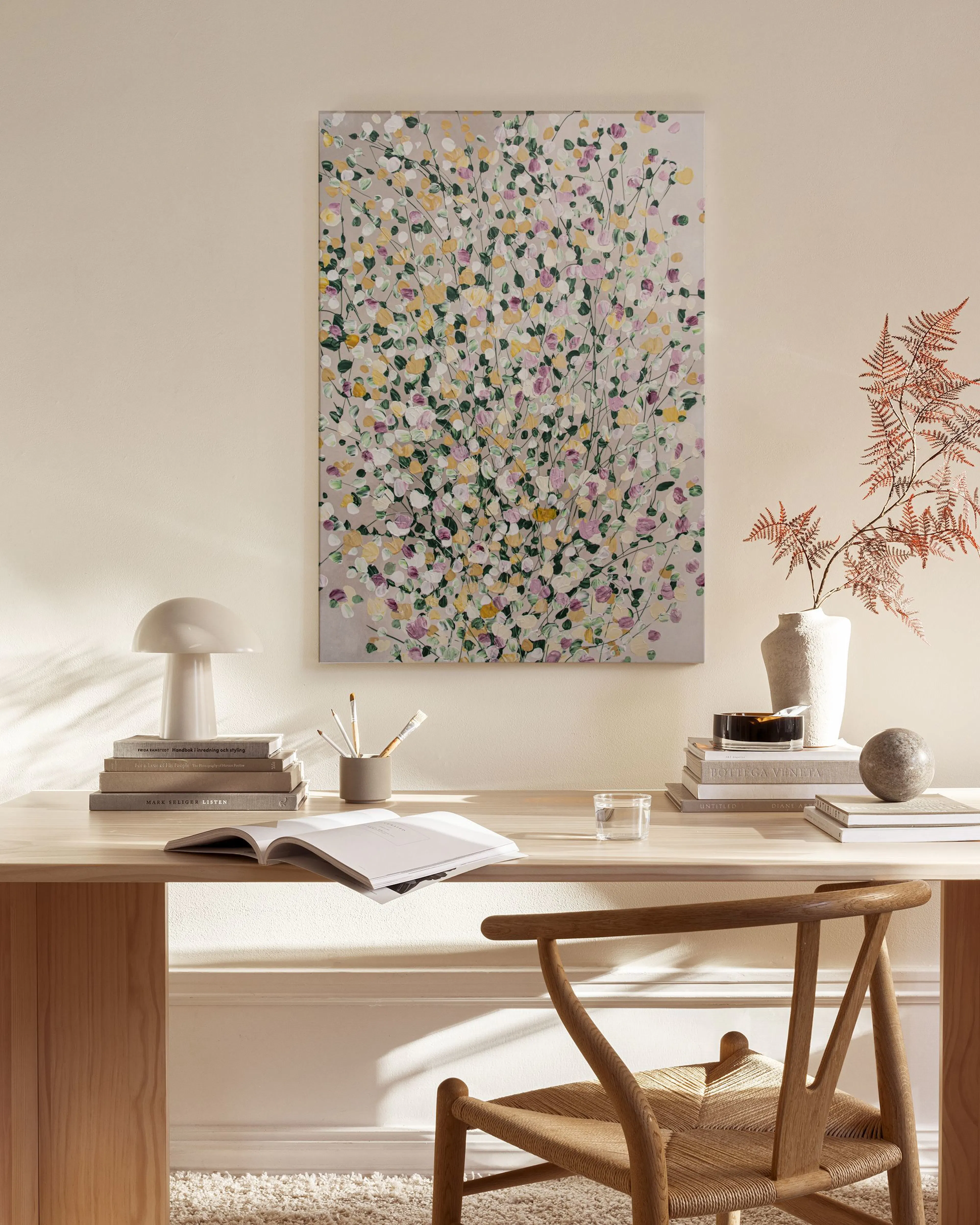 A canvas print of a floral abstract with pink, yellow, and green dots, hanging in a minimalist living room.