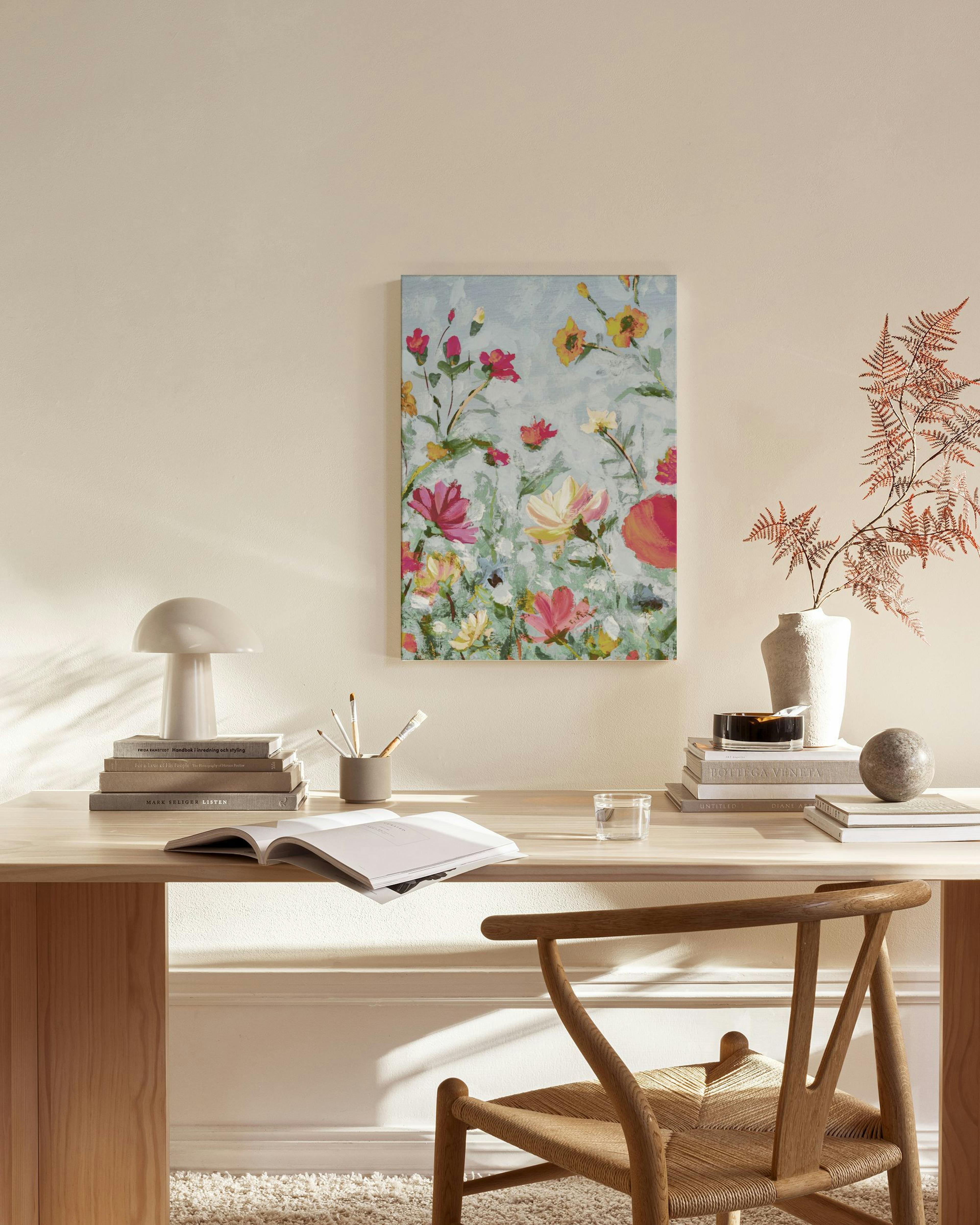 Toile florale aux couleurs vives avec des fleurs rouges, jaunes et roses sur fond bleu clair, accrochée dans un salon moderne.
