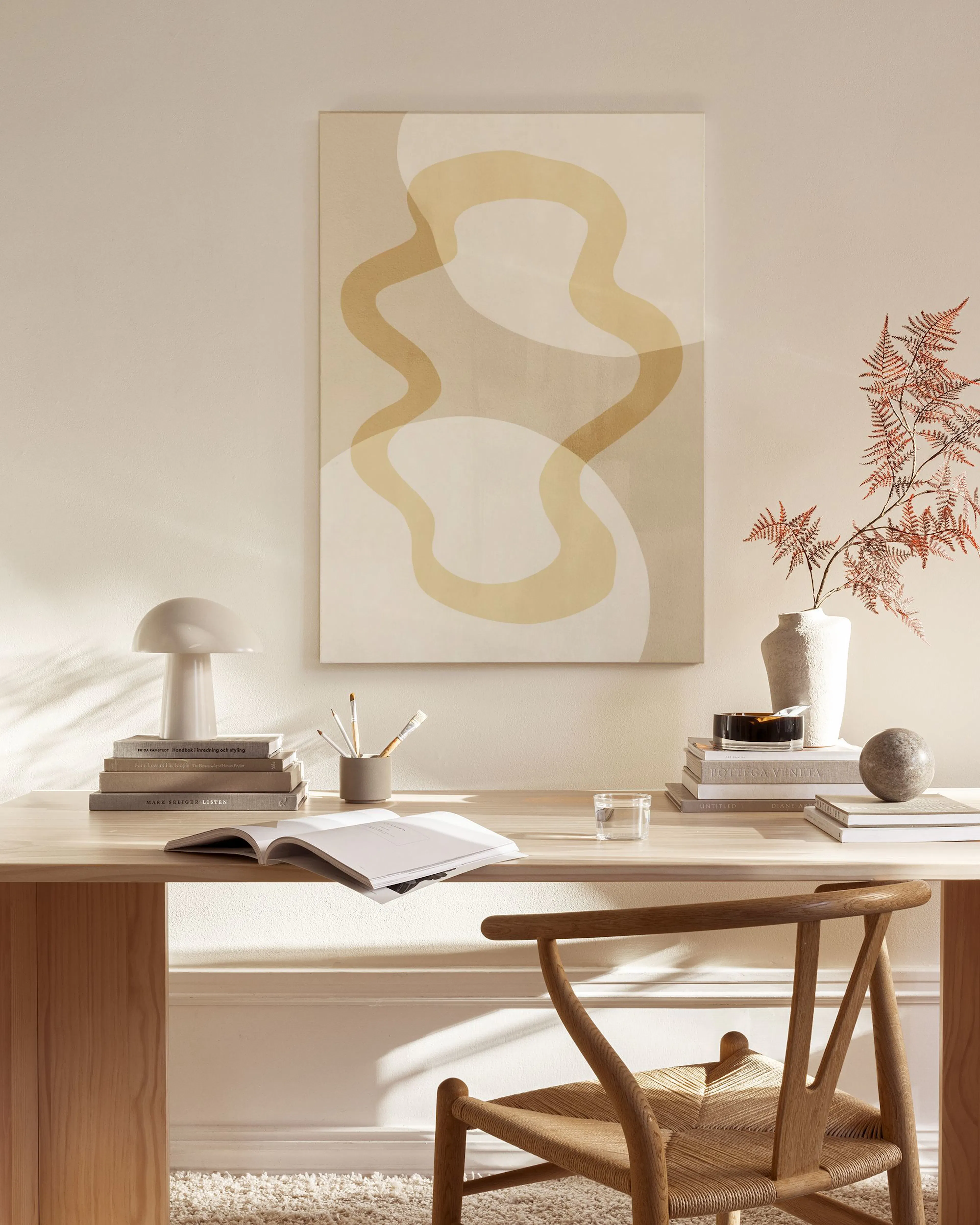 Abstract canvas print with organic, flowing shapes in beige and yellow hues, hanging in a minimalist living room.