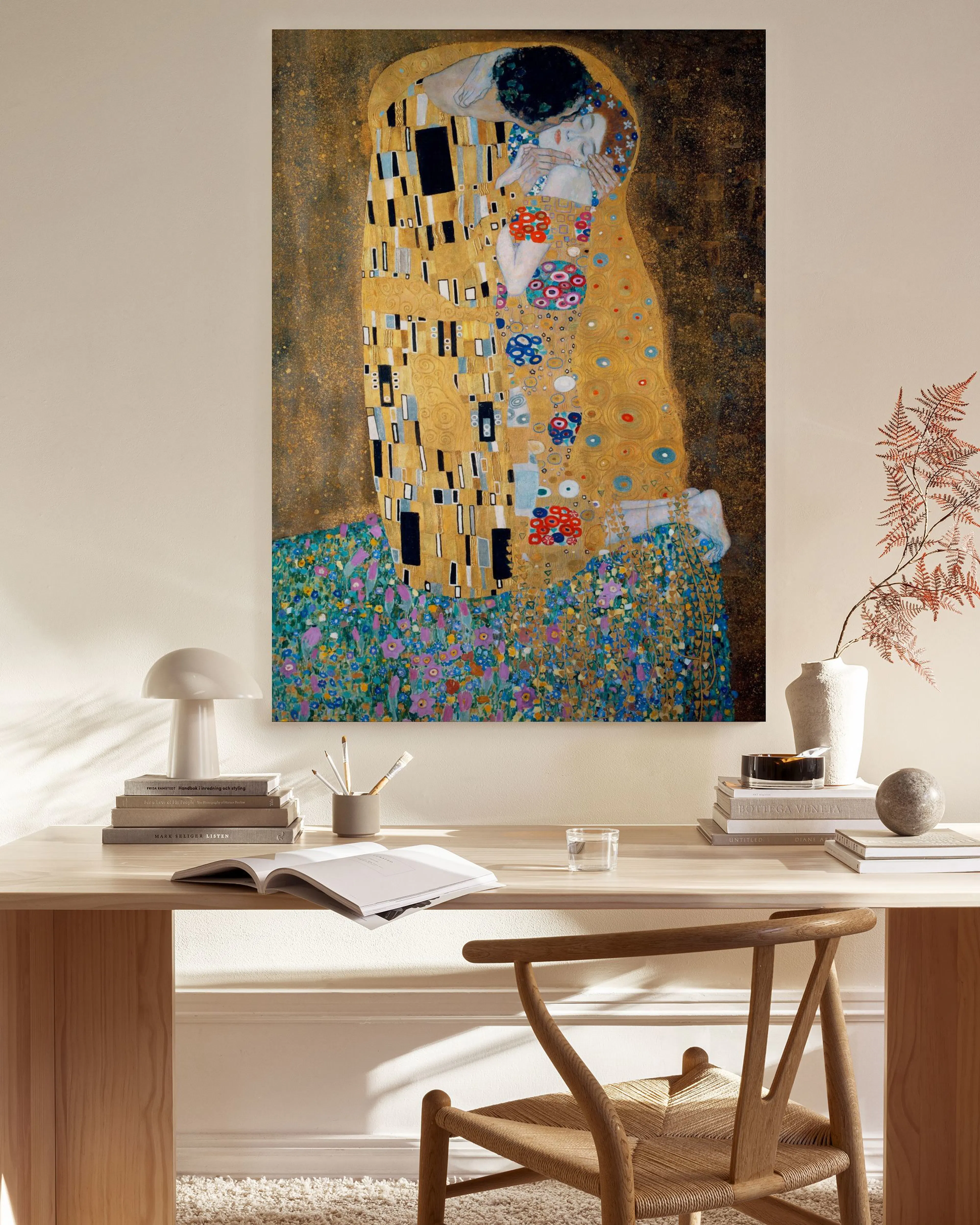 Leinwandbild von Gustav Klimts Der Kuss in Goldtönen mit bunten Ornamenten, hängend in einem hellen Wohnzimmer über einem Sidebo